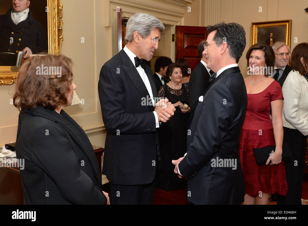 With Teresa Heinz Kerry looking on, U.S. Secretary of State John Kerry greets Comedy Central show host Stephen Colbert, who emceed the 2014 Kennedy Center Honors, before a dinner that the Secretary hosted in honor of the 2014 Kennedy Center event, at the U.S. Department of State in Washington, D.C., on December 6, 2014. Stock Photo