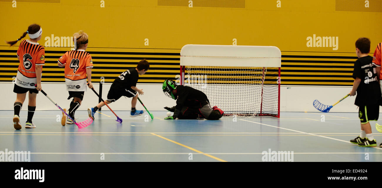 Children boys schoolchildren playing floorball (floor hockey) match in school gym hall with