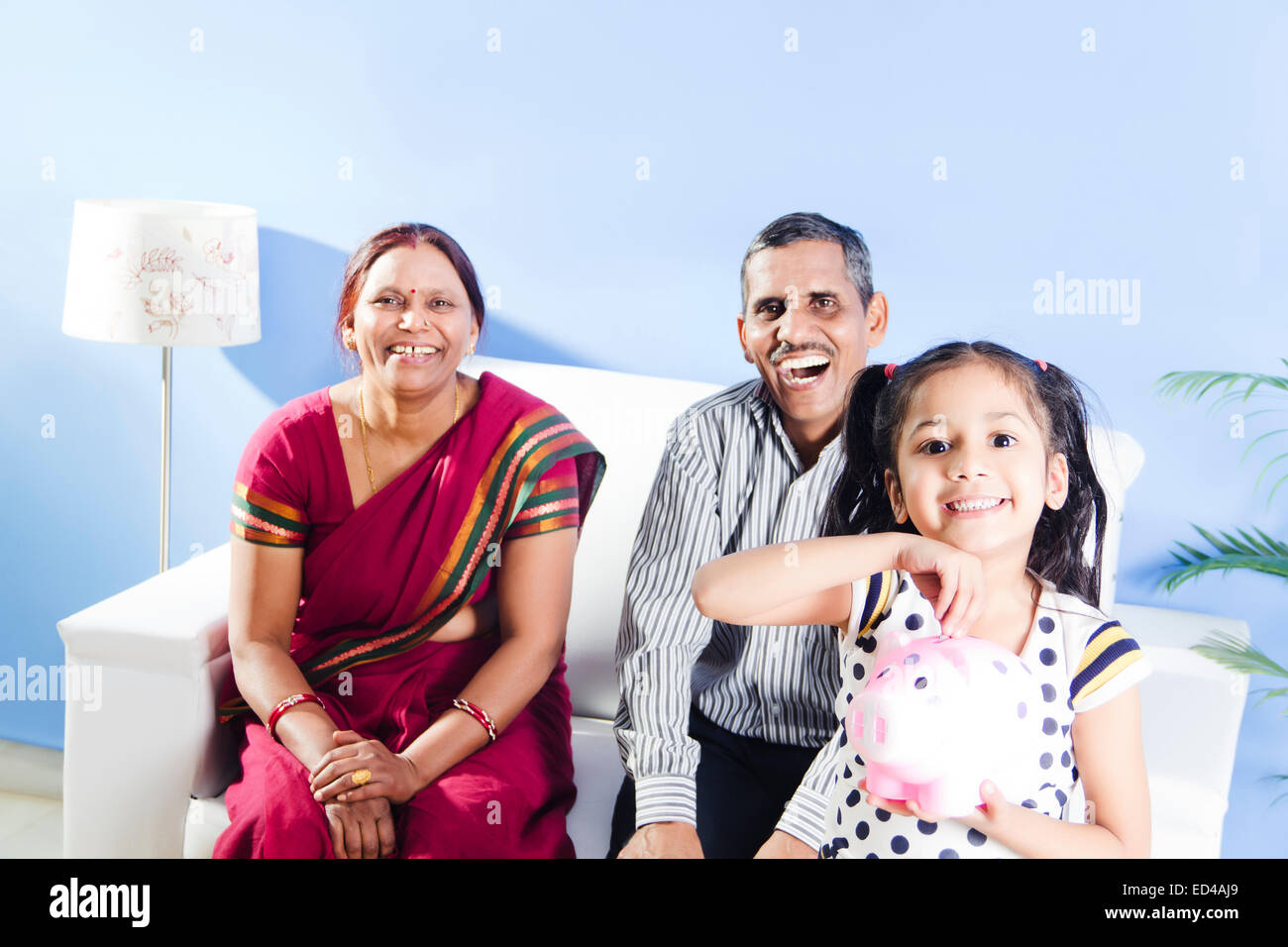 indian Parents with child saving money Piggy Bank Stock Photo