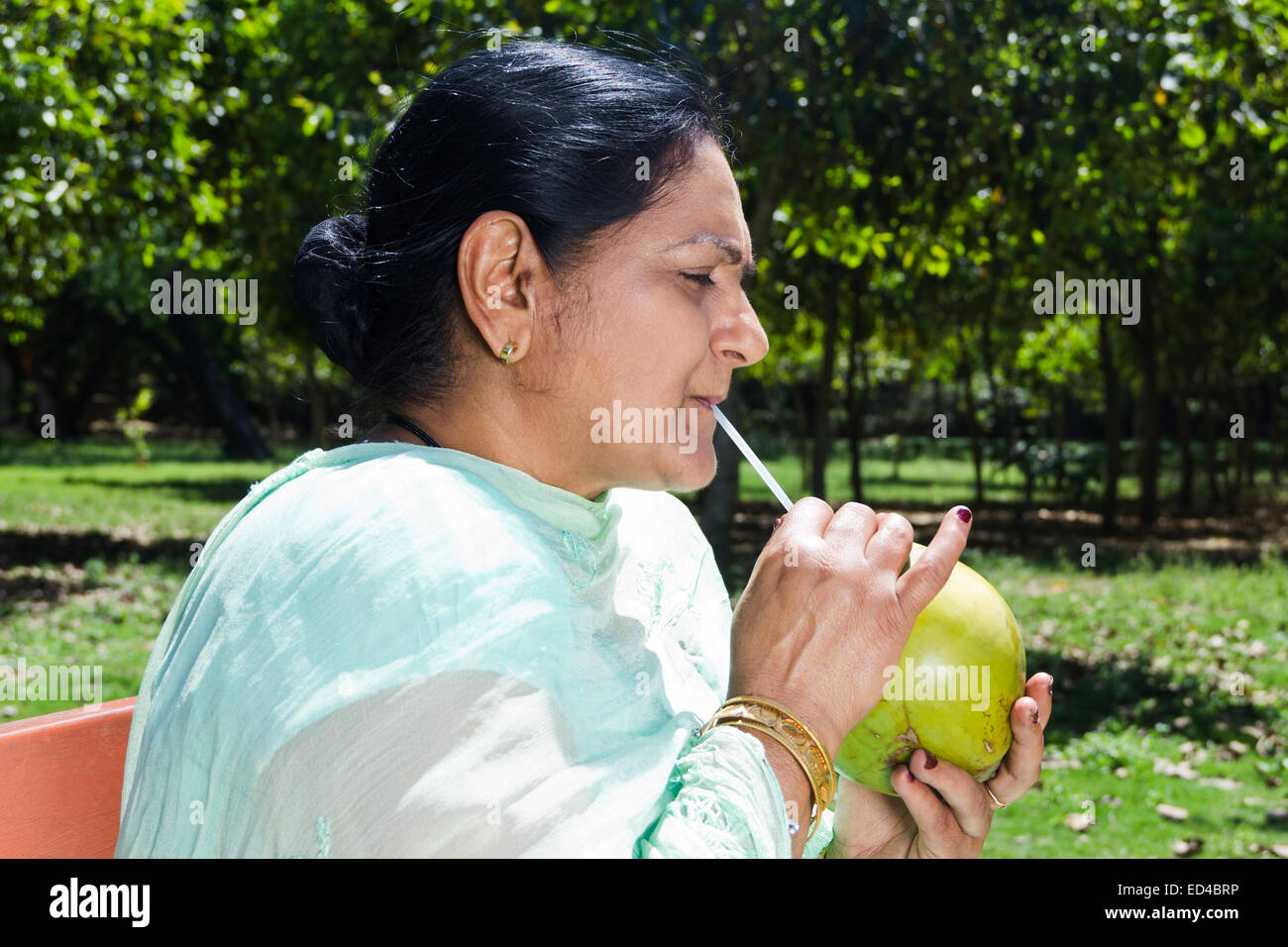 indian Old woman park enjoy Drinking Coconut Stock Photo
