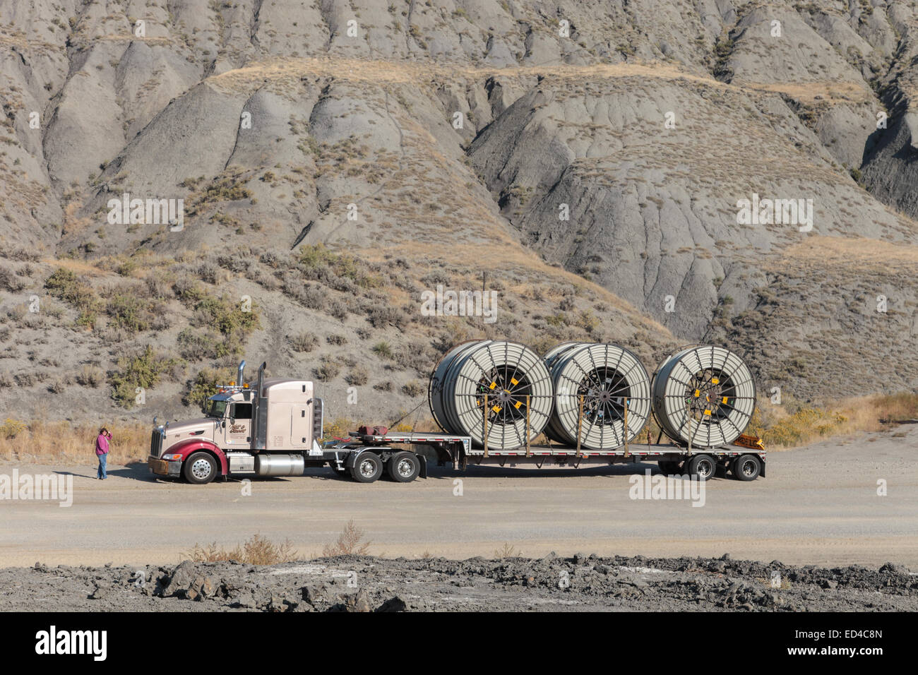 An American Peterbilt 379 semi truck hauling reels of HDPE plastic pipe on a flatbed trailer for the oil industry and fracking sites in the USA Stock Photo