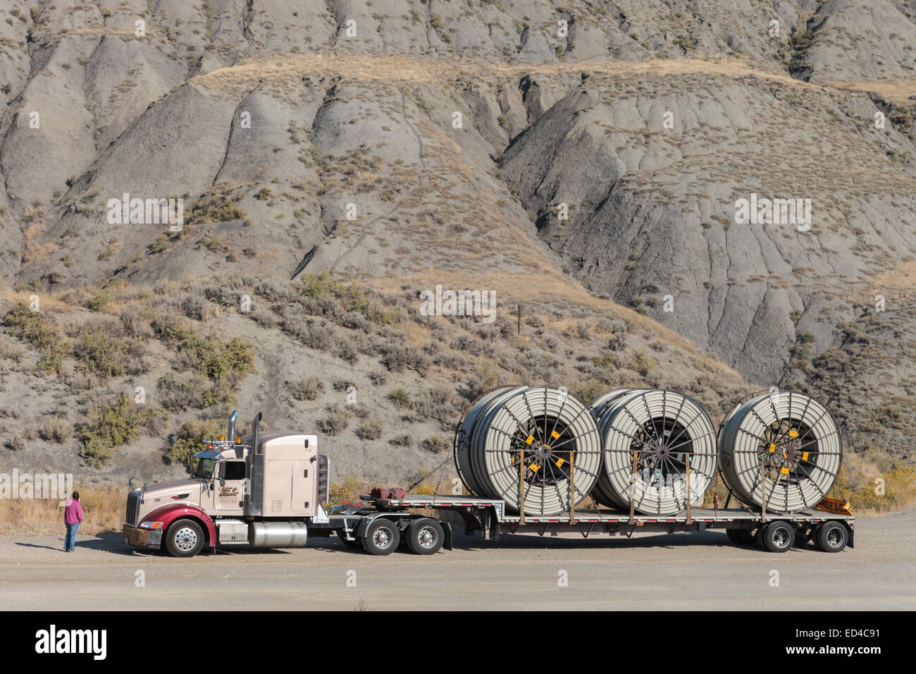 An American Peterbilt 379 semi truck hauling reels of HDPE plastic pipe on a flatbed trailer for the oil industry and fracking sites in the USA Stock Photo