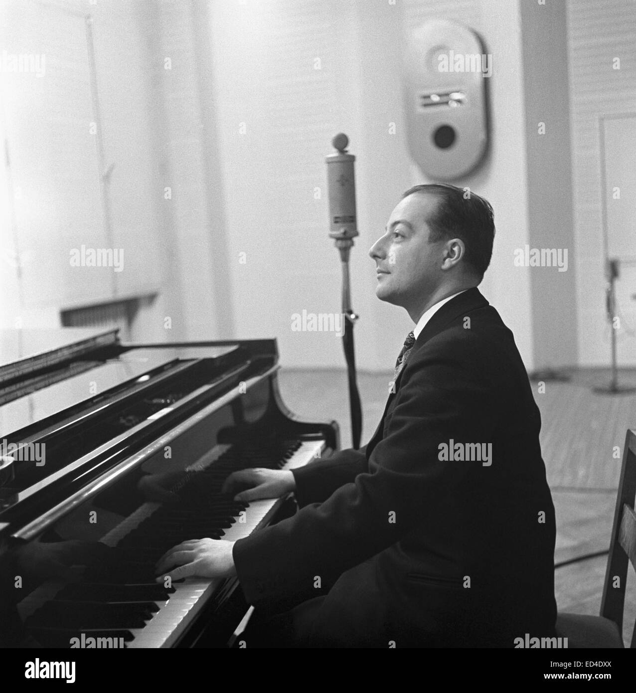 Conductor George de Godzinsky playing a grand piano in a radio studio, ca 1935. Stock Photo