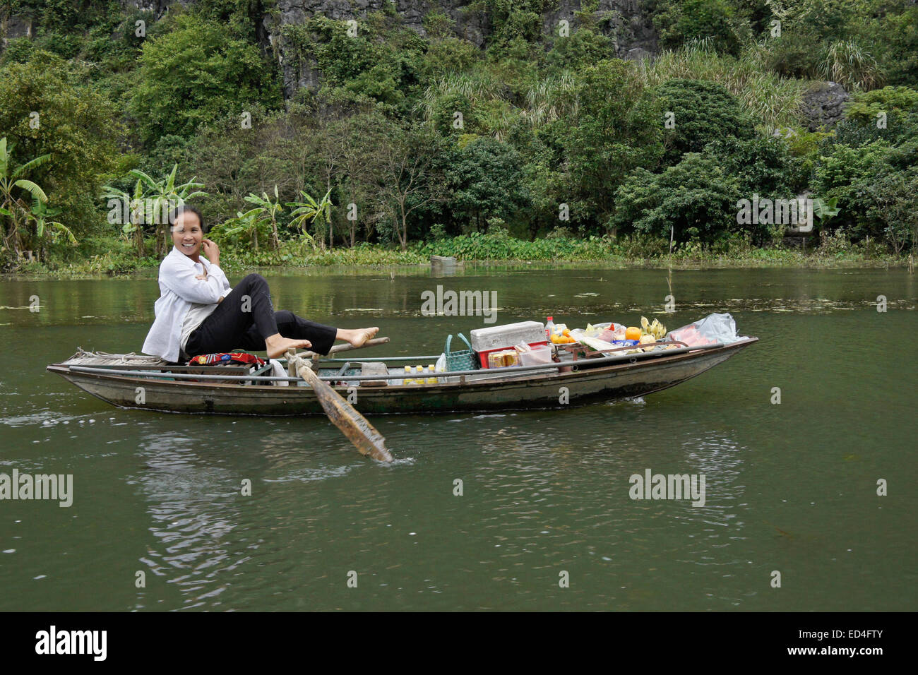 Woman rowing boat with feet, Ngo Dong River, Tam Coc, Vietnam Stock Photo
