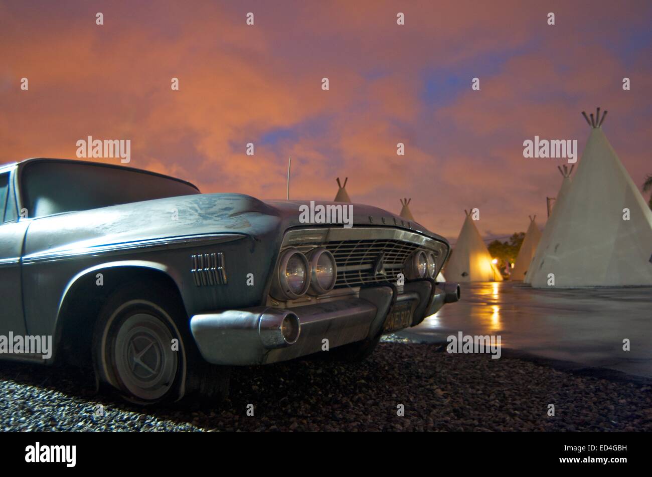 Retired from a heyday of getting its kicks on Route 66, a classic automobile stands guard outside a vintage wigwam motel. Stock Photo