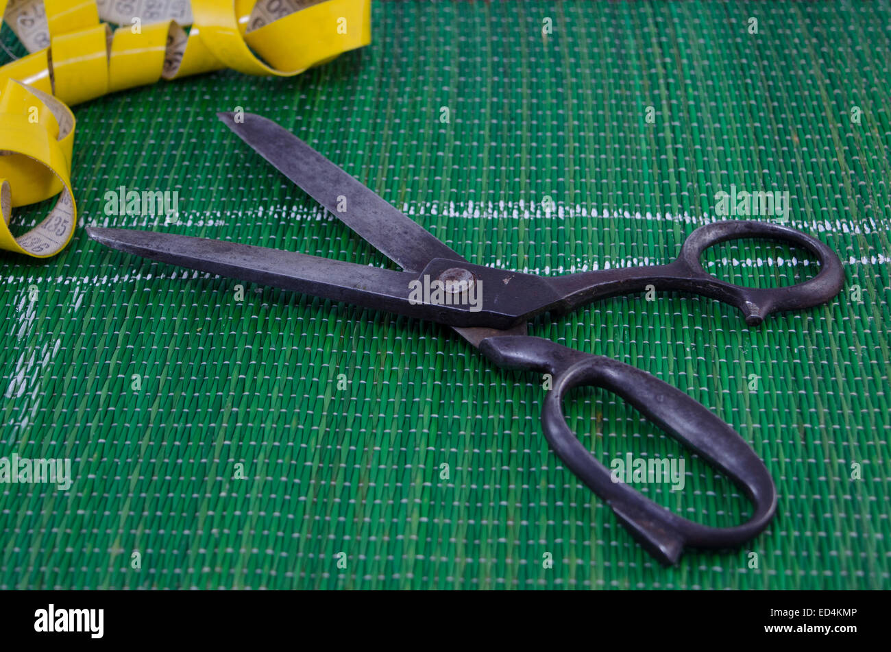 Old scissors and a tape measure on green background Stock Photo