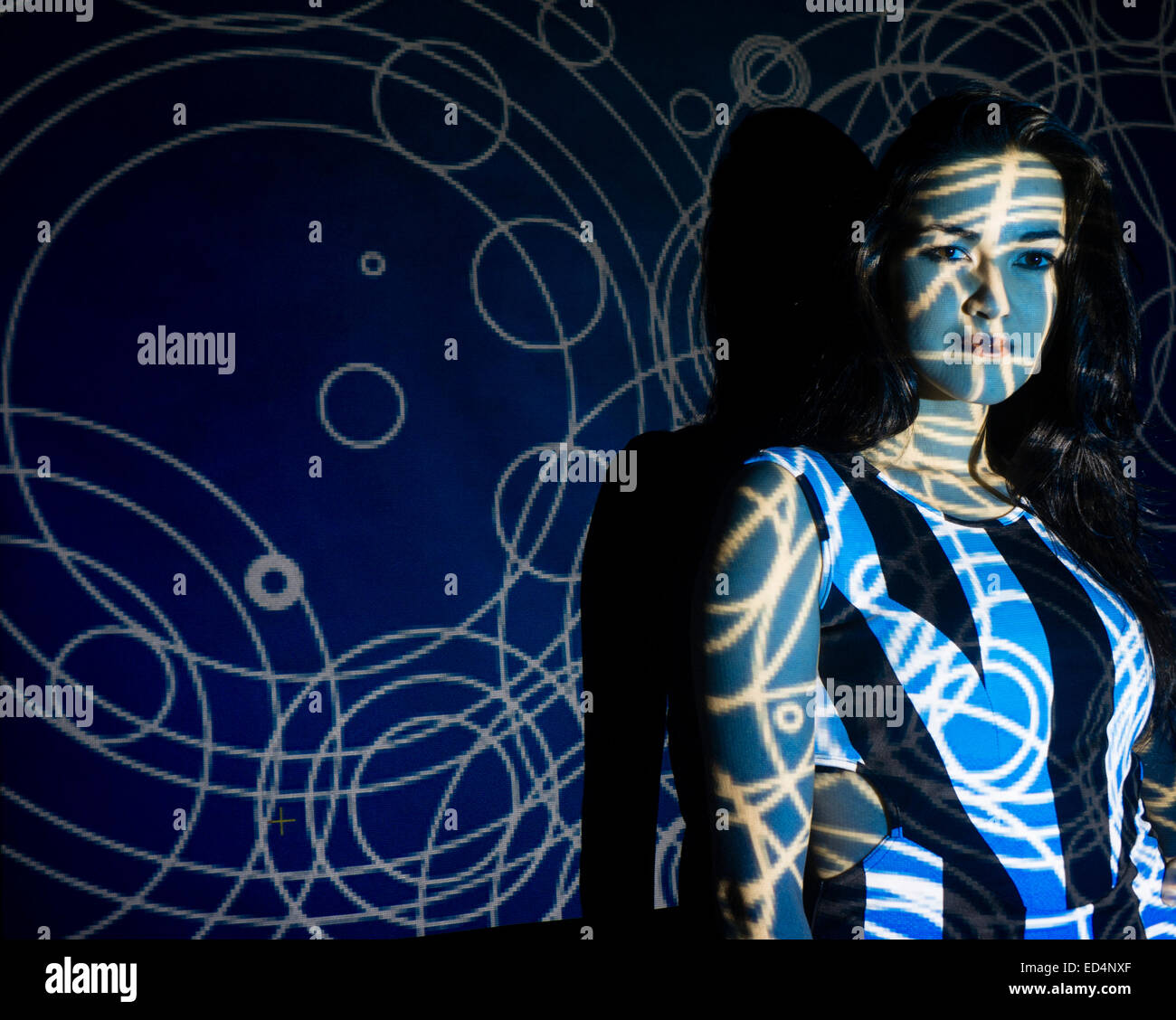 Digital Art: a young woman girl with a swirling spiral digital image pattern projected onto her face. Stock Photo