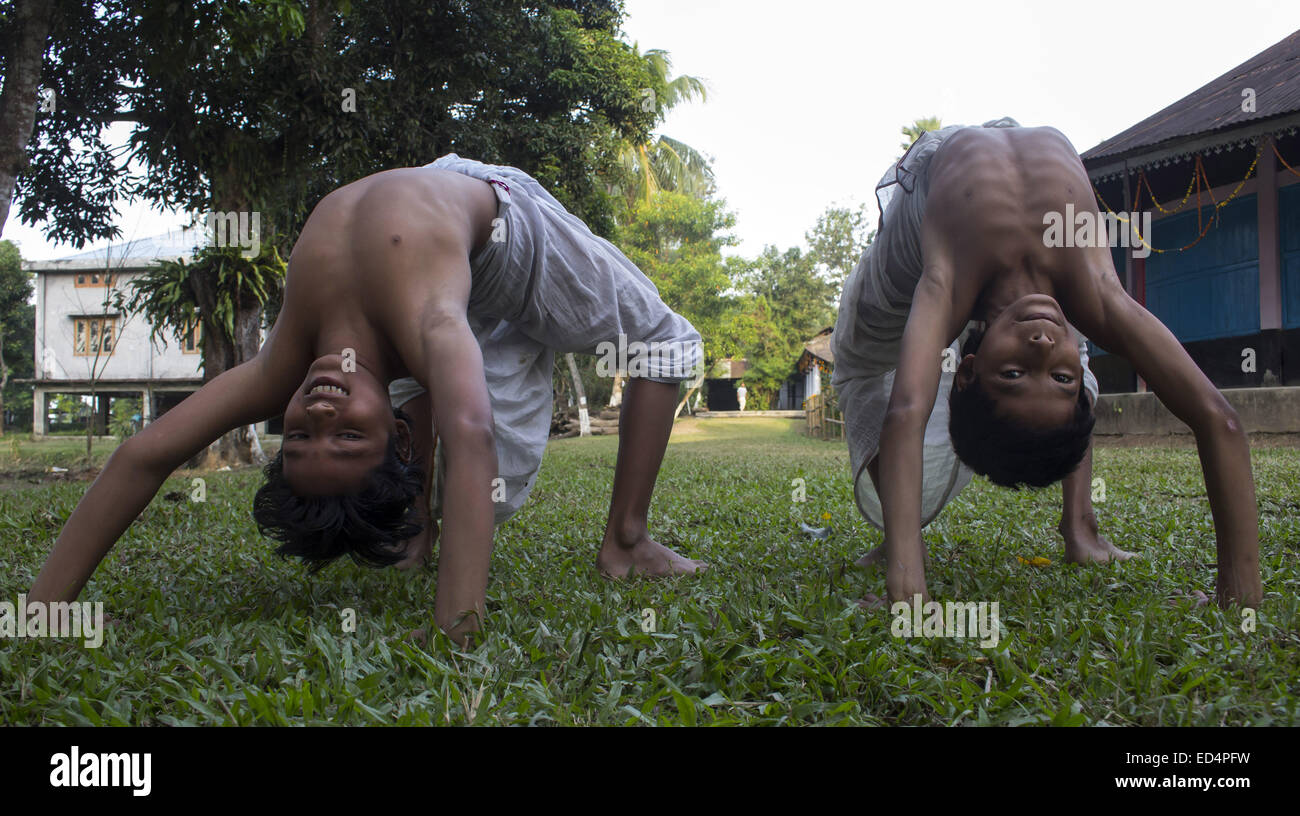 Majuli, Assam, India. 27th Dec, 2014. Two junior bhakats (monks) practice Sankardeva's 'Mati Akhora', medieval Indian ground aerobics at the Dakhinpat Satra, a Neo-Vaishnavite monastery on the Majuli river. Satras (monasteries) follow the practice of teaching children from age of 5-7 years. There they learn the monastic order by a well drawn out system of daily routine and rituals under the supervision of senior monks that take responsibility for individual children as the foster fathers. In the process, the children come to learn various aspects of sattra discipline, including the performing Stock Photo