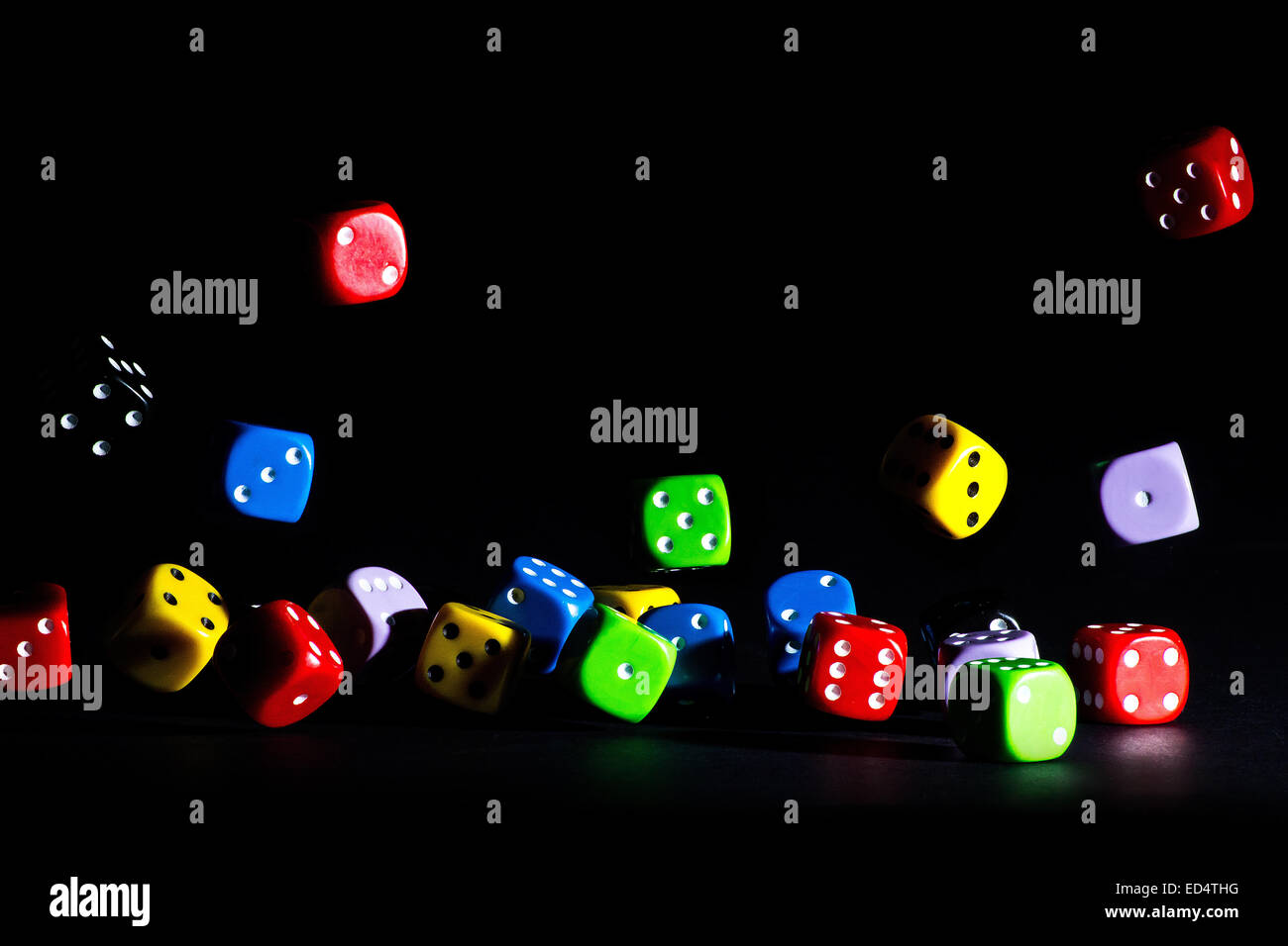 colored dice jumping on a dark background Stock Photo