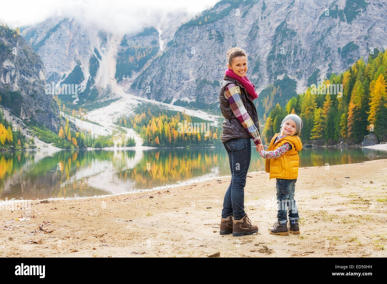 Full length portrait of happy mother and baby on lake braies in south tyrol, italy Stock Photo
