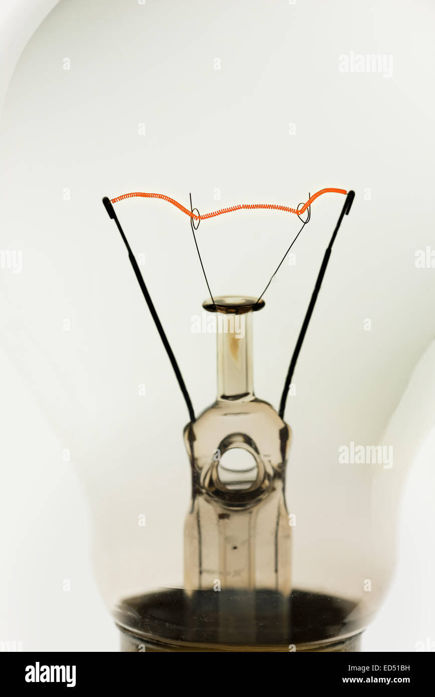 Glowing supported red hot tungsten wire filament in clear light bulb