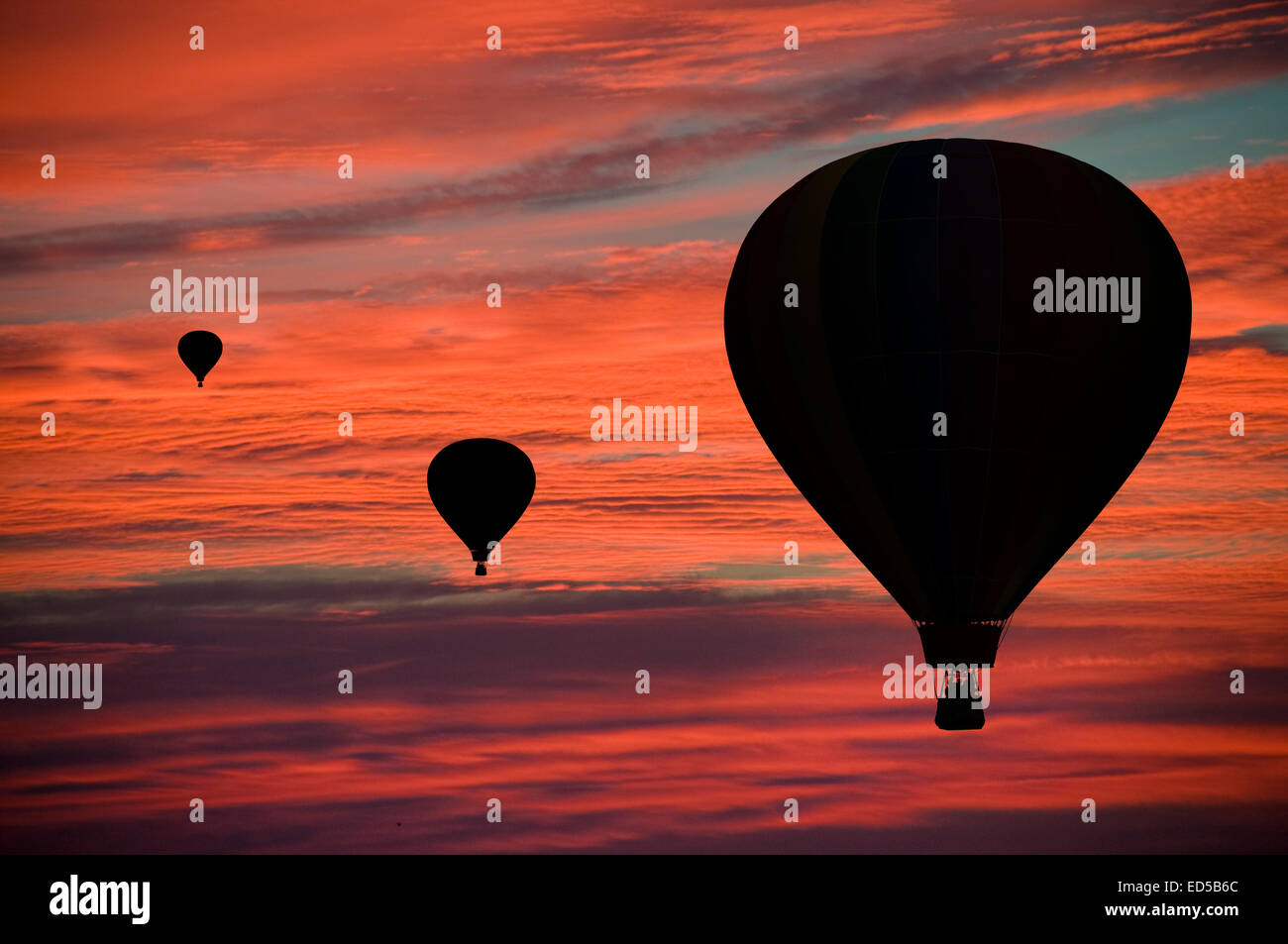 Hot-air balloons floating among pink and orange clouds at dawn Stock Photo
