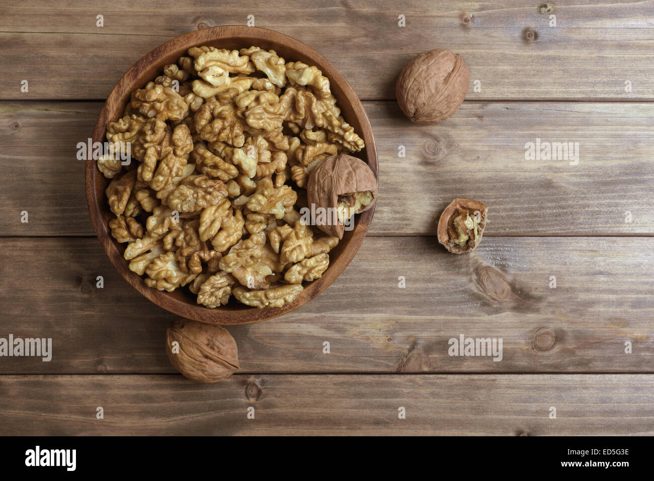 Walnuts in wooden bowl on wooden table Stock Photo