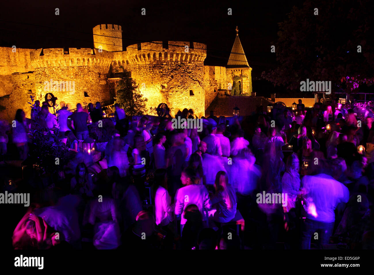 People dancing at the Terrassa night club in Belgrade, Serbia. The Zindan Gate of the Kalmegdan fortress stands illuminated in t Stock Photo