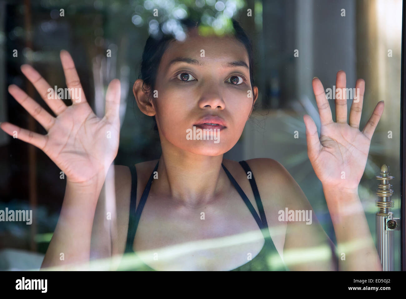 Asian woman looking out through window Stock Photo