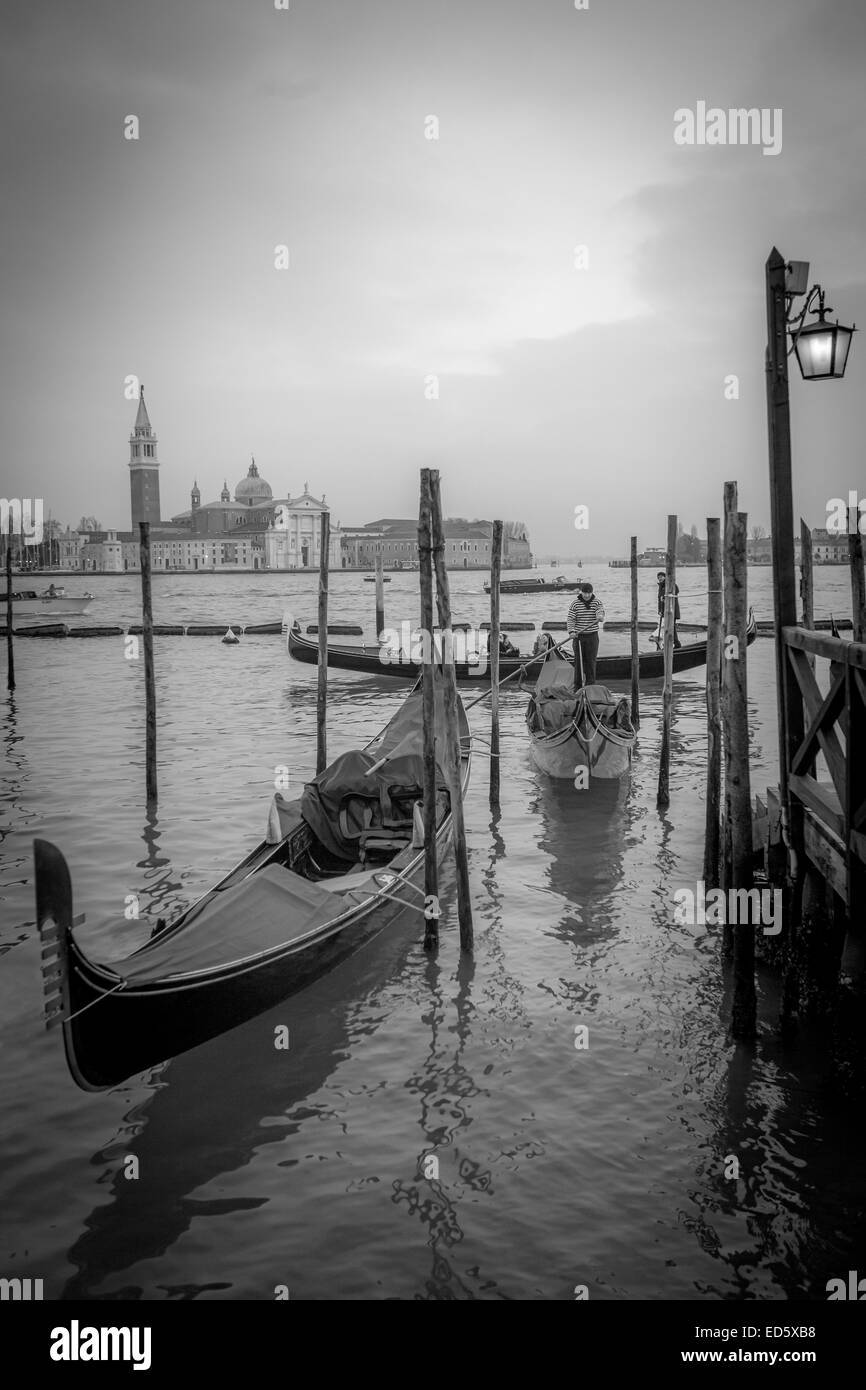 VENICE - Gondolier mooring gondola by Saint Mark's Square with view of Saint Giorgio Maggiore cathedral, Italy Stock Photo