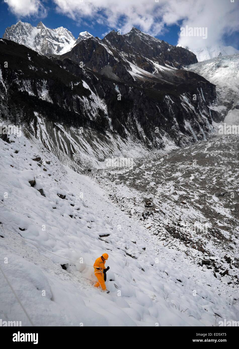 Garz, Sichuan, China. 28th Dec, 2014. A sanitation worker is cleaning the trash which throw by tourists dangerously on the glacier of conch gully in Garz, Sichuan, China on 28th December, 2014. © TopPhoto/Alamy Live News Stock Photo