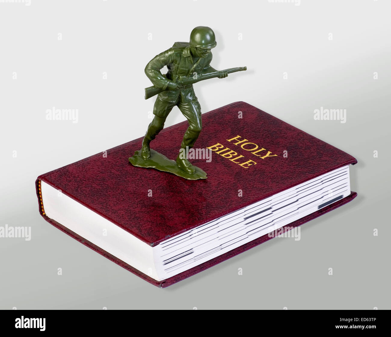 Toy green soldier standing on bible. Stock Photo