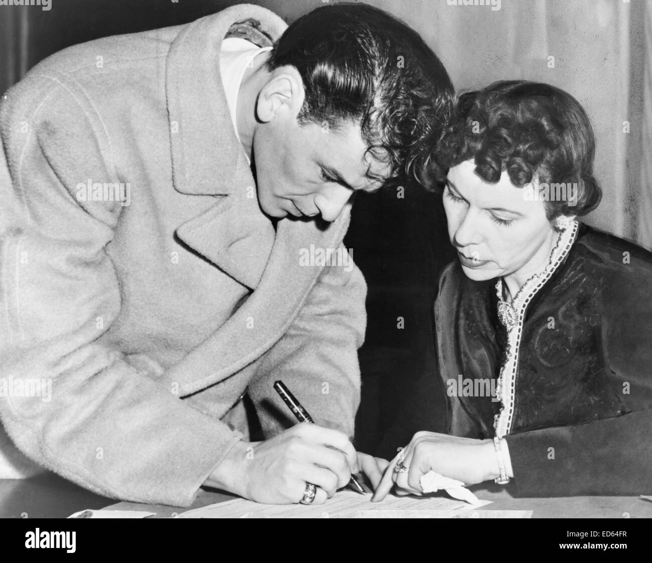 Frank Sinatra signs his induction papers while Chief Clerk Mrs. Mae E. Jones helps out at local board No. 19-160 Danforth St., Jersey City, 1943 Stock Photo