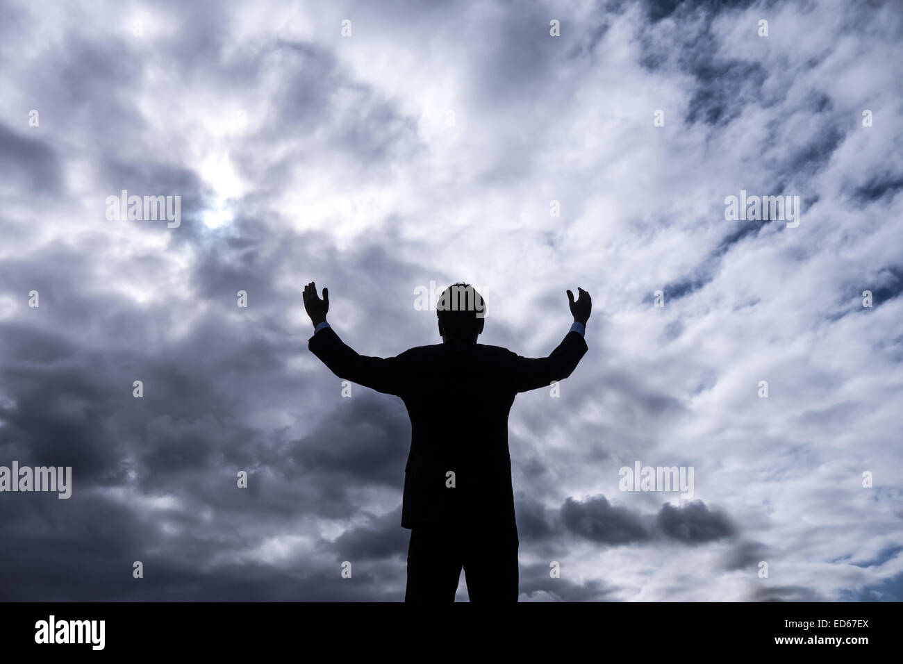 businessman upholding arms and stormy clouds Stock Photo