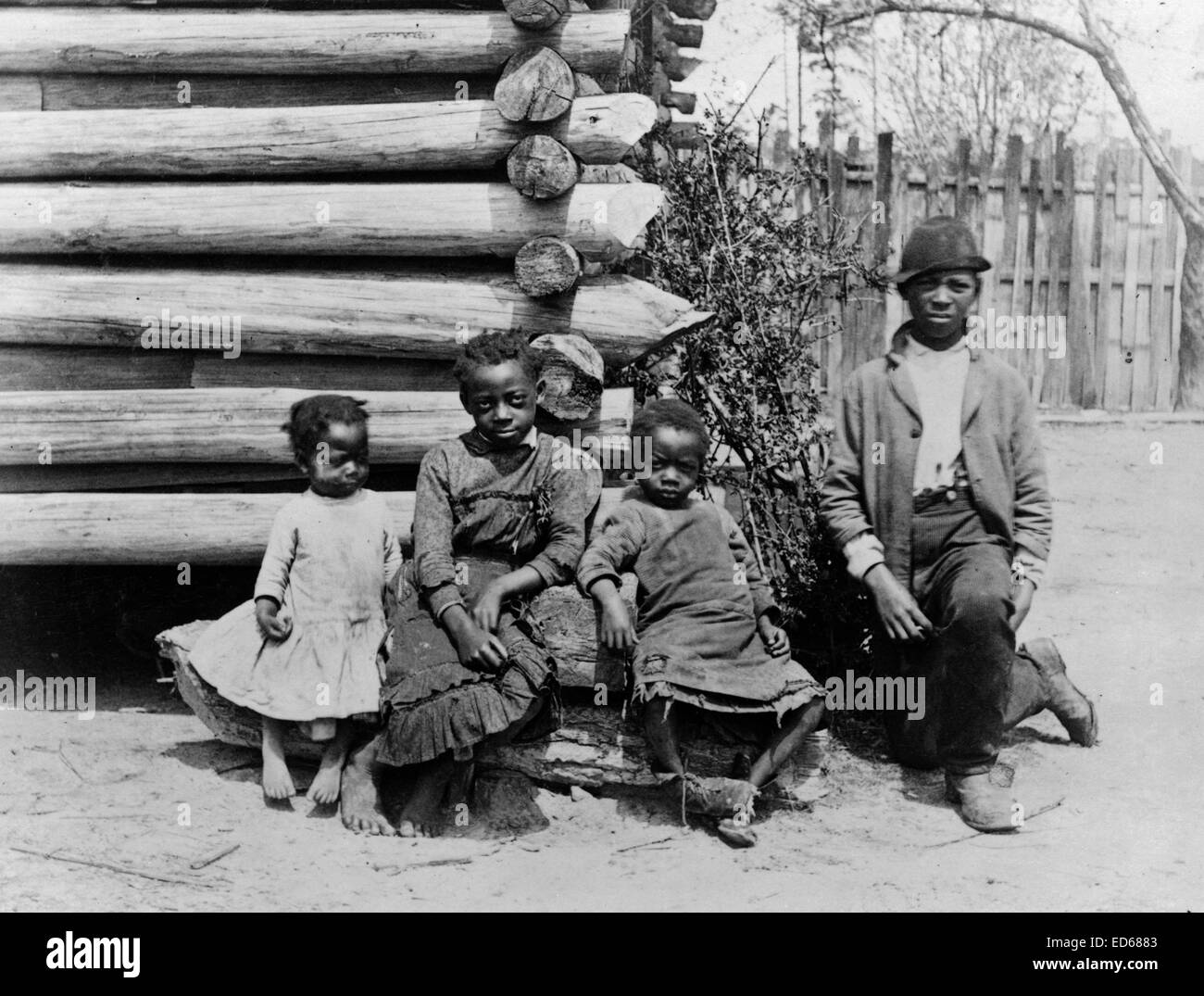 African American man and three children posed at corner of log building, near Thomasville, Georgia. between 1884 and 1891. Stock Photo
