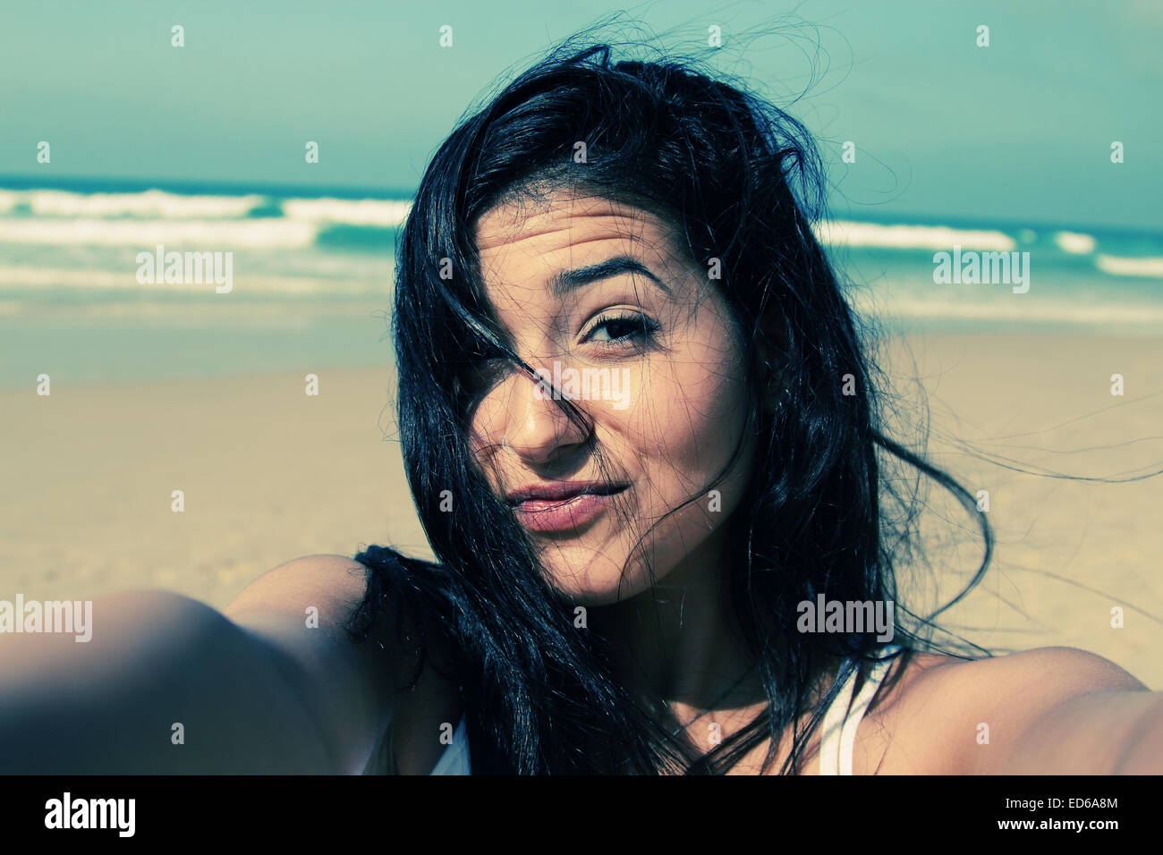 Beautiful girl smiling on the beach with the sand, sea and blue sky in the background. Selfie. Stock Photo