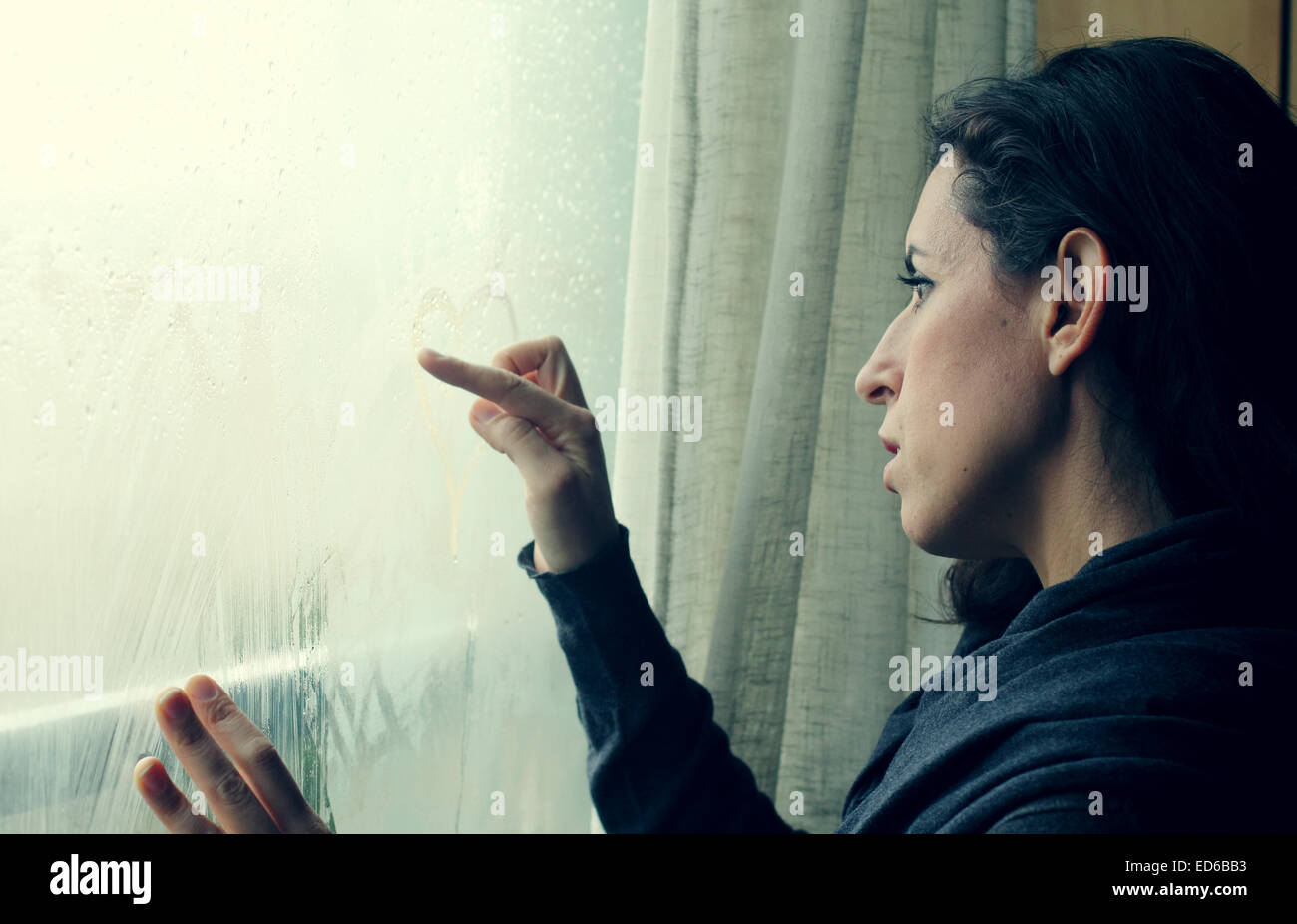 mid adult woman looking out of the window Stock Photo