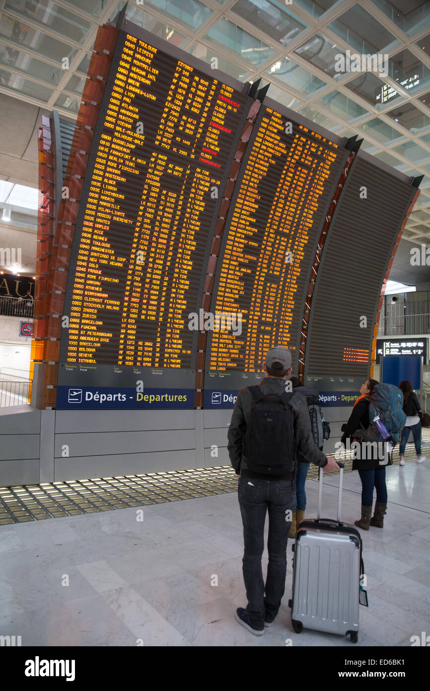 flight information board Paris airport traveler passenger man luggage Stock Photo
