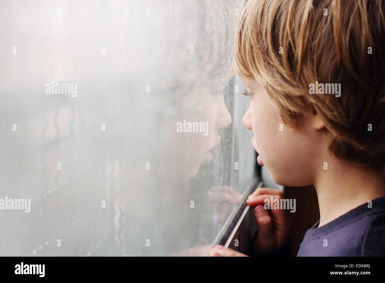 Cute 6 years old boy looking through the window Stock Photo