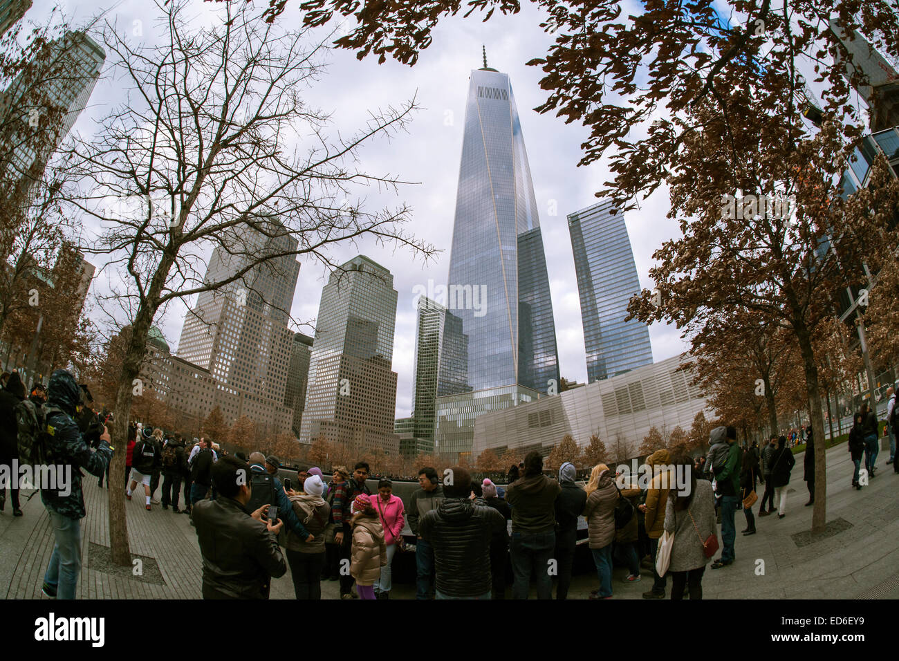 One World Trade Center rises over visitors to the National September 11 Memorial & Museum in New York on Christmas, Thursday, December 25, 2014. The memorial consists of twin memorial pools on the footprints of the World Trade Center and a plaza planted with more than 400 swamp white oak trees. The names of the 2983 victims of 9/11 and the February 1993 WTC attack are inscribed around the base of the pools. (© Richard B. Levine) Stock Photo