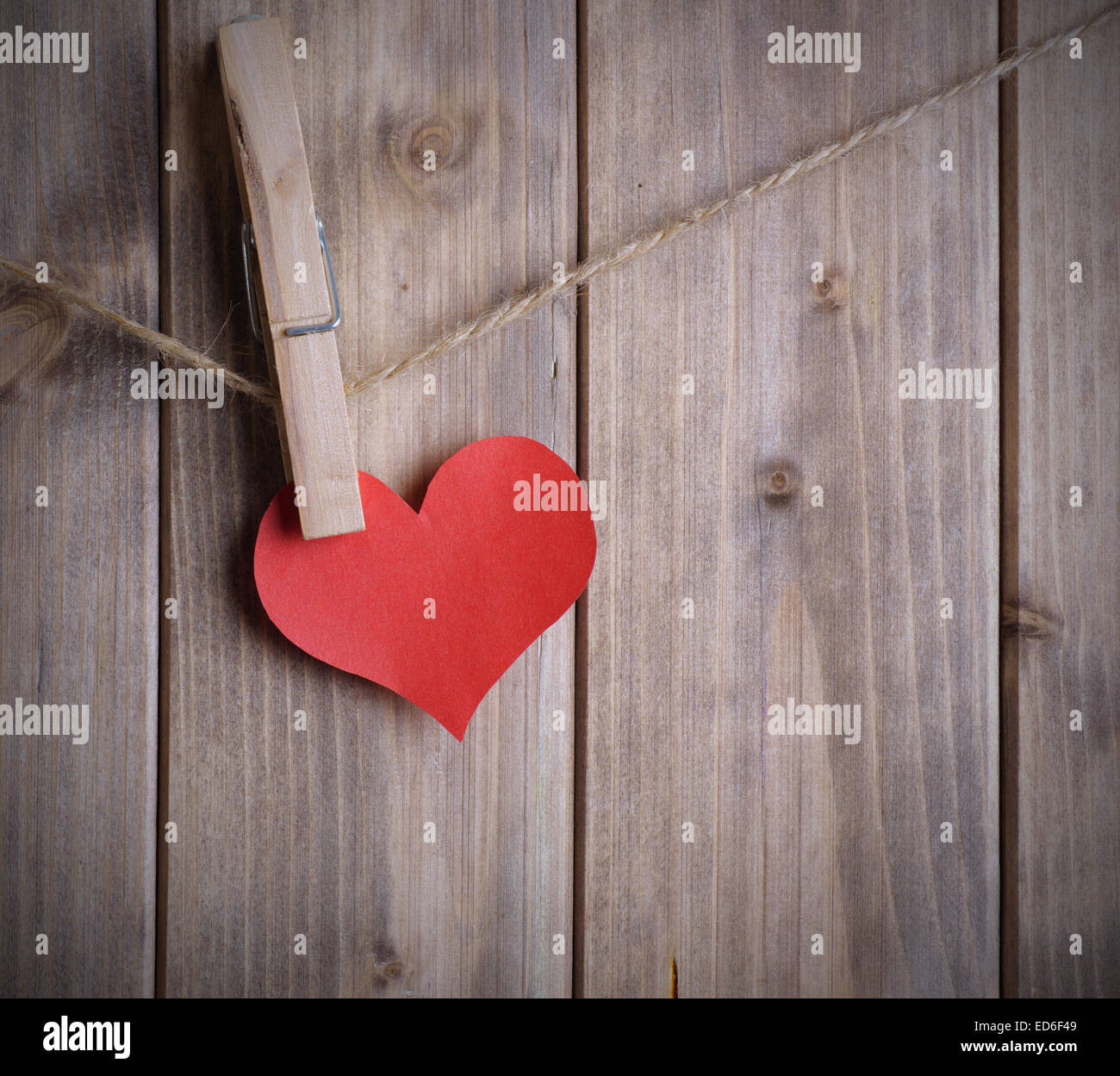 red heart made of paper with clothespin hanging on a rope and wooden ...