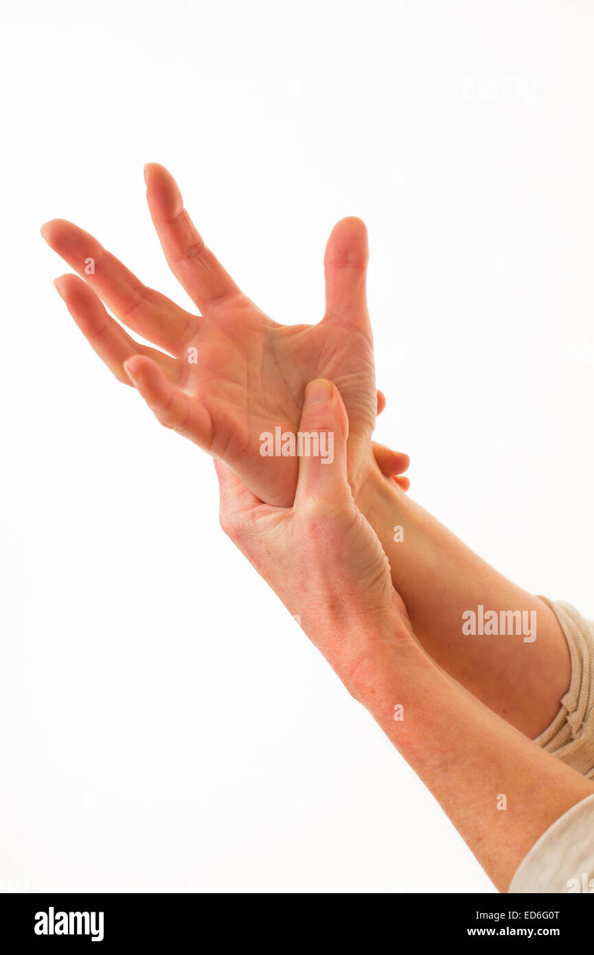 Close up of the hands of a forty year old caucasian woman with painful arthritis in the joints of her hand wrist and fingers, rubbing her wrist for pain relief, against a white background. UK Stock Photo