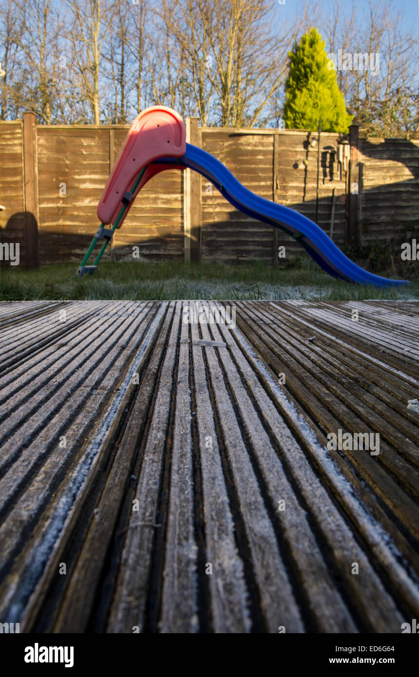 Slippery frozen decking in front of a garden child slide. A dangerous combination Stock Photo