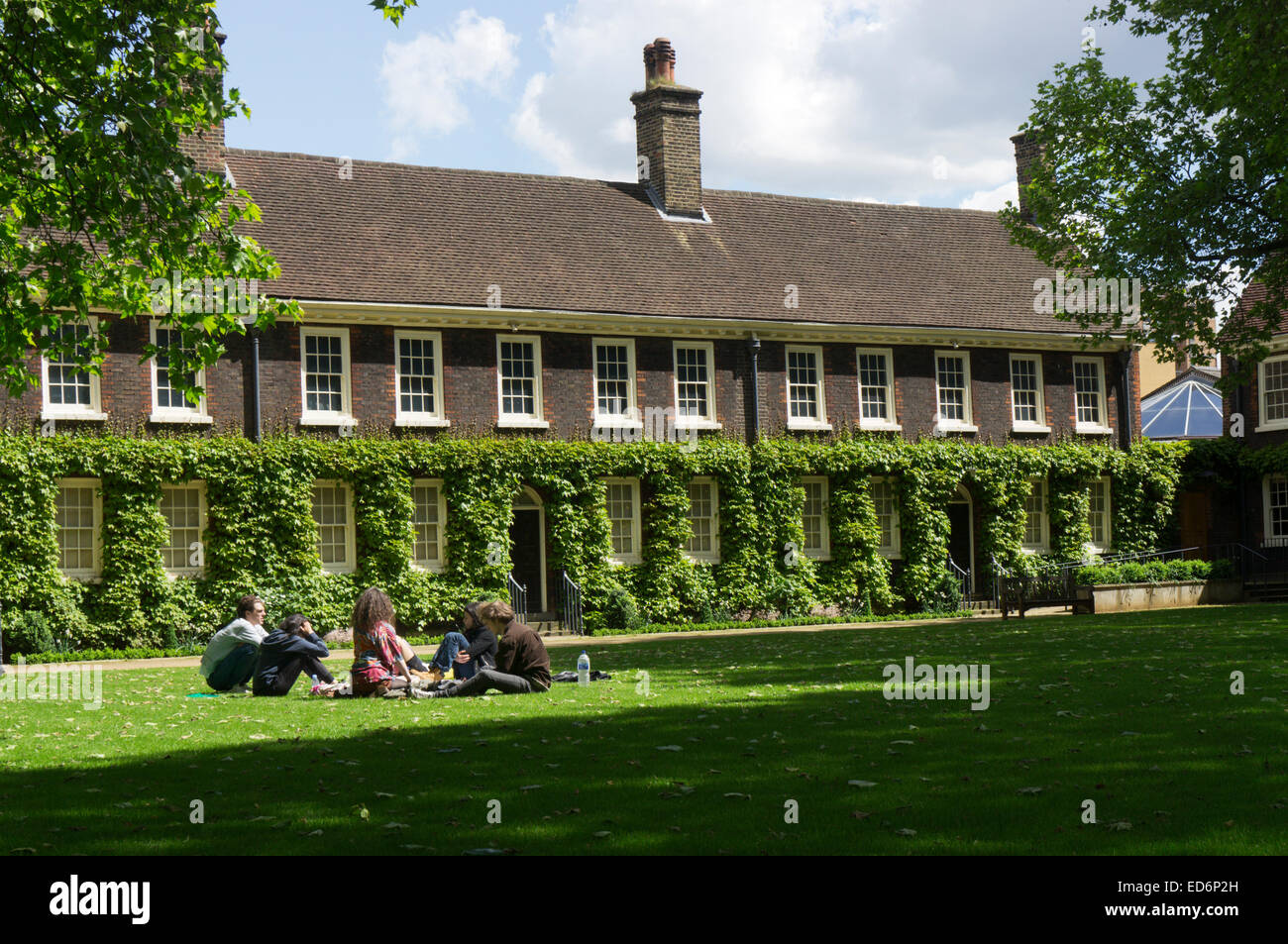 Young people relaxing on the grass lawn in front of the Geffrye Museum, now the Museum of the Home, in Shoreditch, East London. Stock Photo