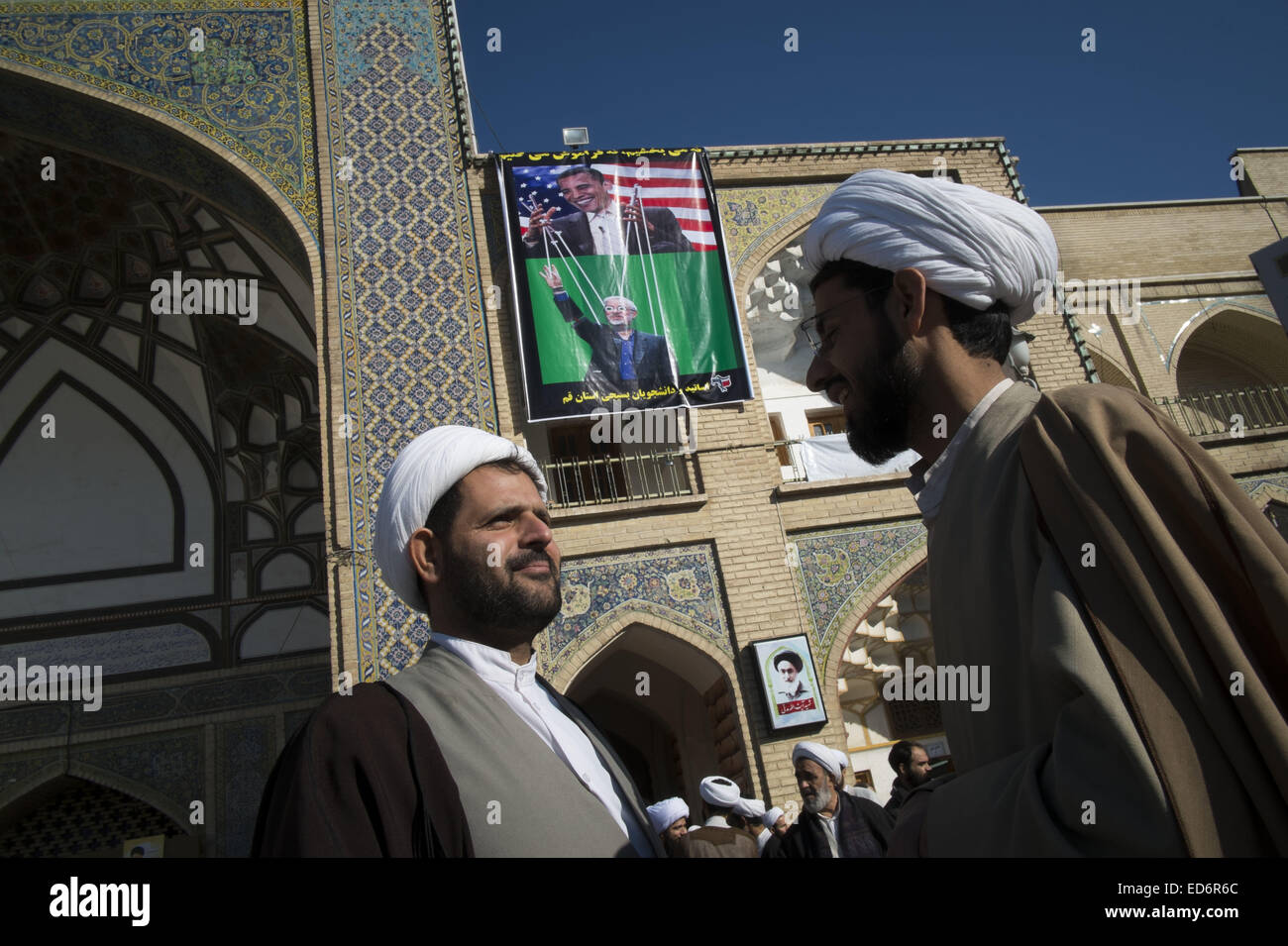 Qom, Iran. 29th Dec, 2014. December 30, 2014 - Qom, Iran - Two Iranian clerics talk with each other as a banner with images of Iran's 2009 presidential candidate MIRHOSSEIN MOUSAVI and the U.S. President BARACK OBAMA is hanged at faziye Seminary in the holy city of Qom 120 km (75 miles) south of Tehran during a rally to mark December 30, 2009 demonstration anniversary. Tens of thousands of Iranians has been demonstrated in the Capital and some other cities on December 30, 201-days after Iran's 2009 Presidential election, in support of Iran's Supreme Leader Ayatollah ALI KHAMENEI and against Stock Photo