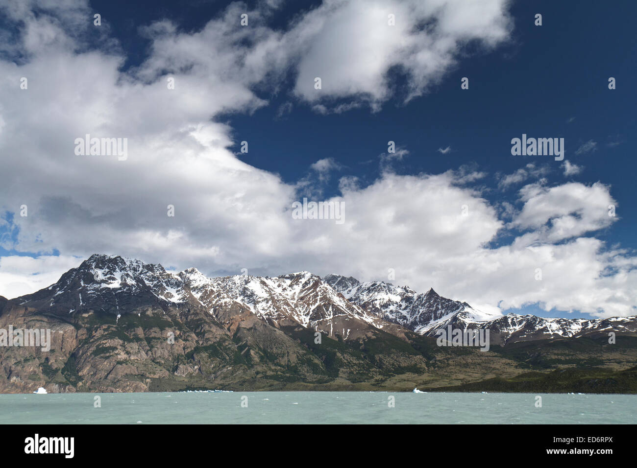 Mountain range on the shores of Lake Viedma In Argentina, Patagonia with icebergs seen floating on the lake. Stock Photo