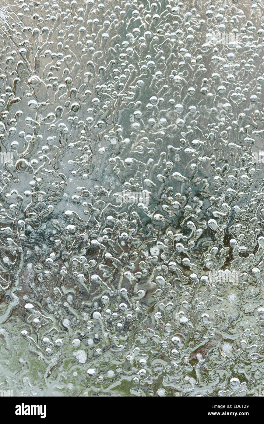 frozen gas bubbles air and stress lines freezing water patterns in ice with radiating lines and trails on bitter cold winter day Stock Photo