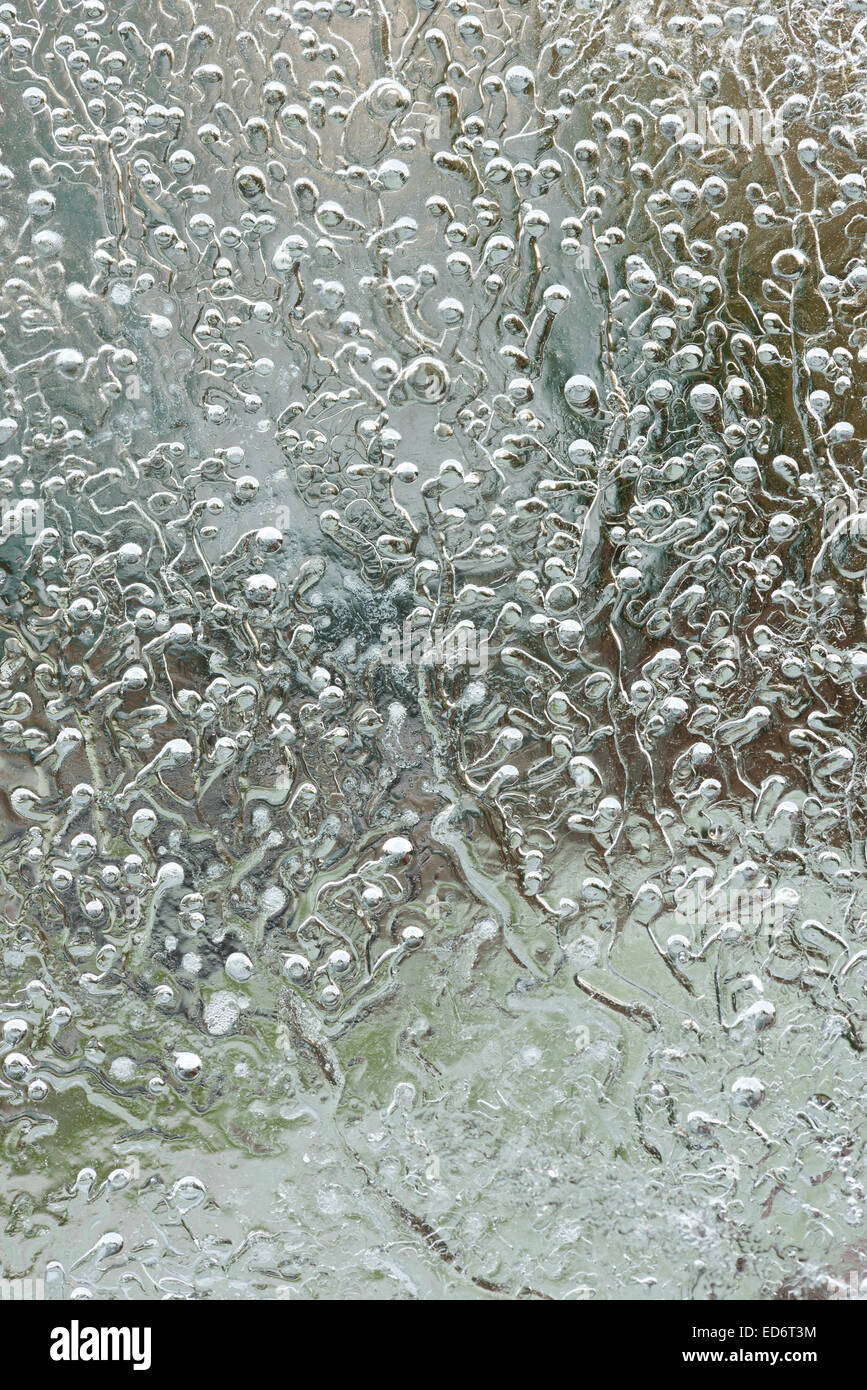 frozen gas bubbles air and stress lines freezing water patterns in ice with radiating lines and trails on bitter cold winter day Stock Photo