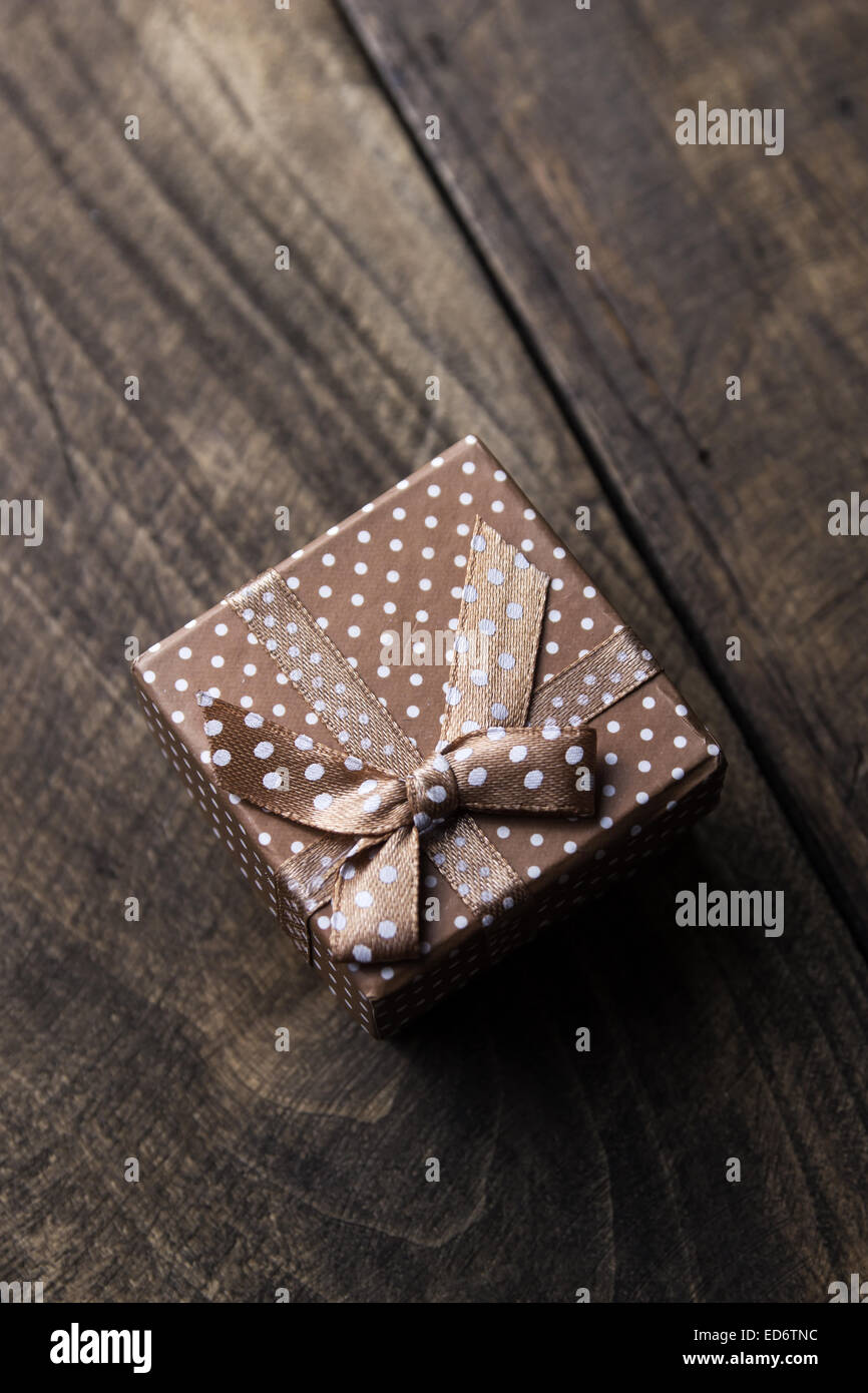 Gift box with ribbon ornament on wooden background. Close up from above Stock Photo