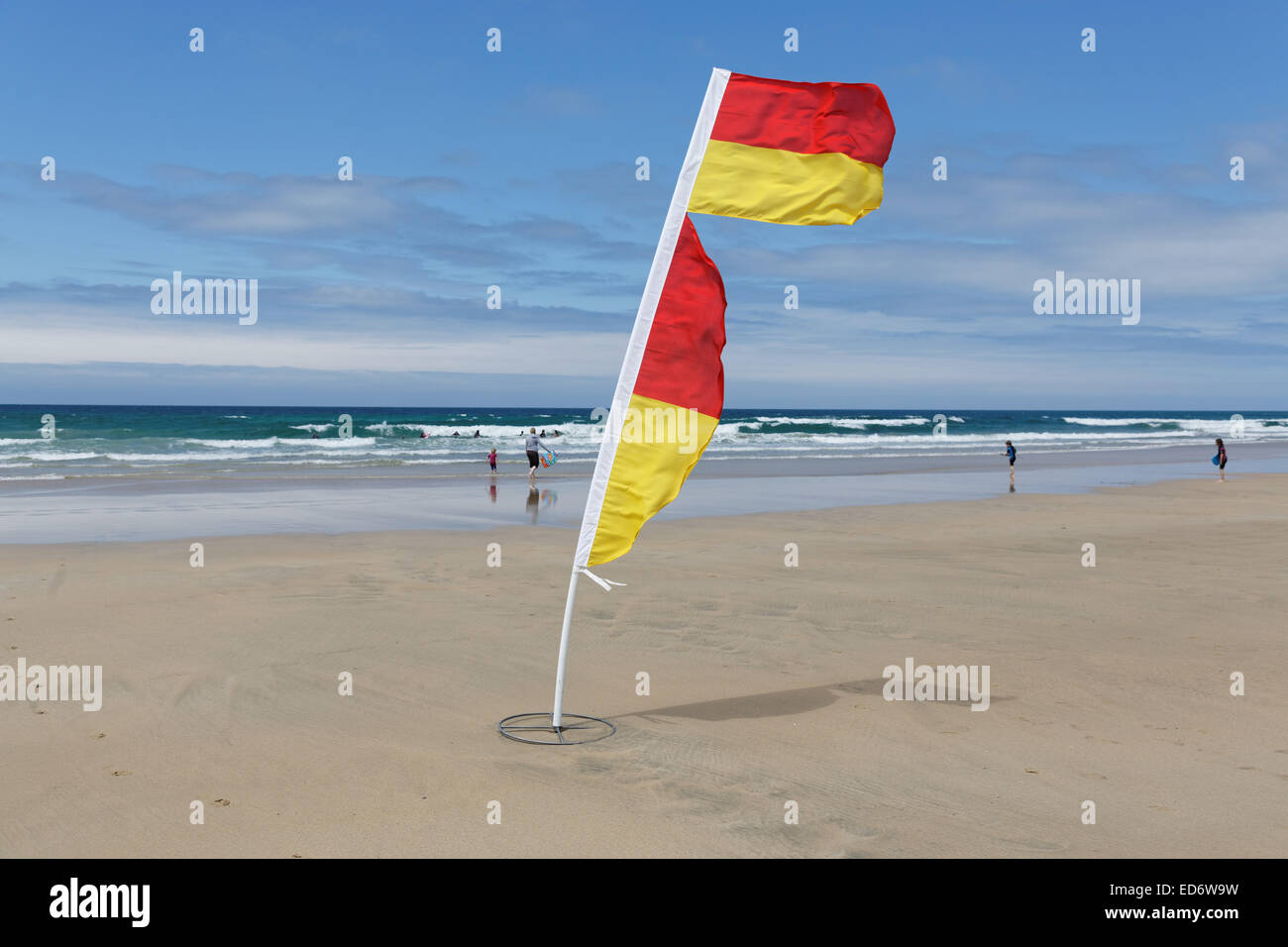 Yellow and red flag of life guards to mark the save part of the fistral beach on a windy day in Newquay, Cornwall, UK. Stock Photo
