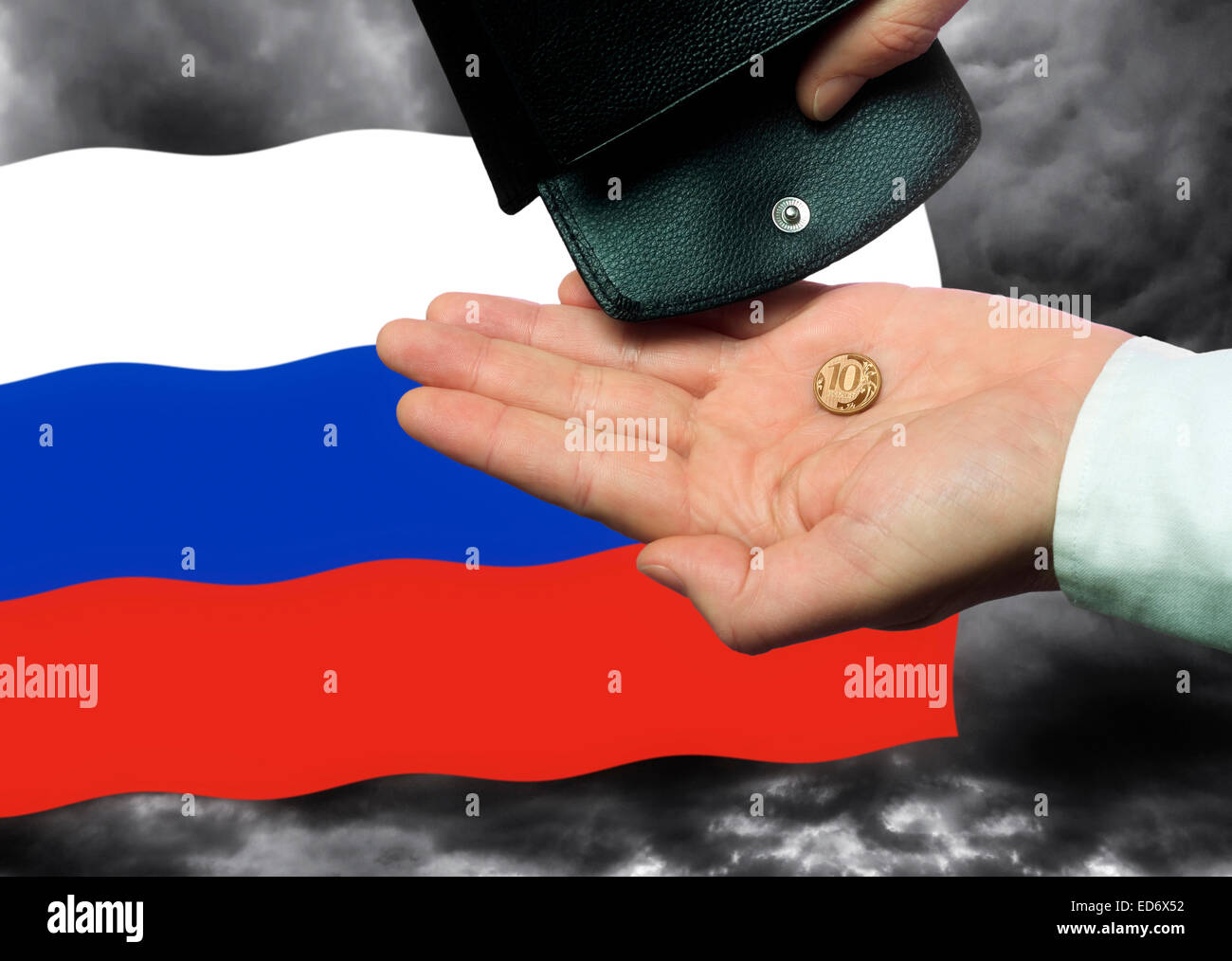 Hand with a ruble coin, Russian flag and purse in front of a dark sky. Stock Photo