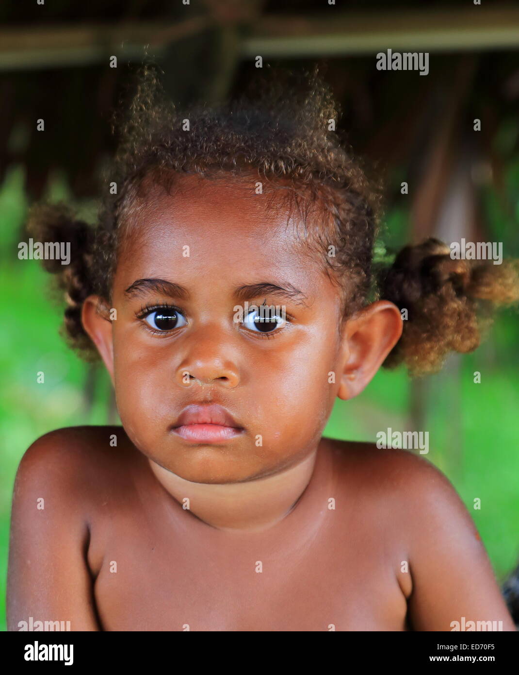 PENTECOSTES,VANUATU-OCTOBER 15, 2014: Little girl accompanies her mother who sells fruit at a stall near the airport on October Stock Photo