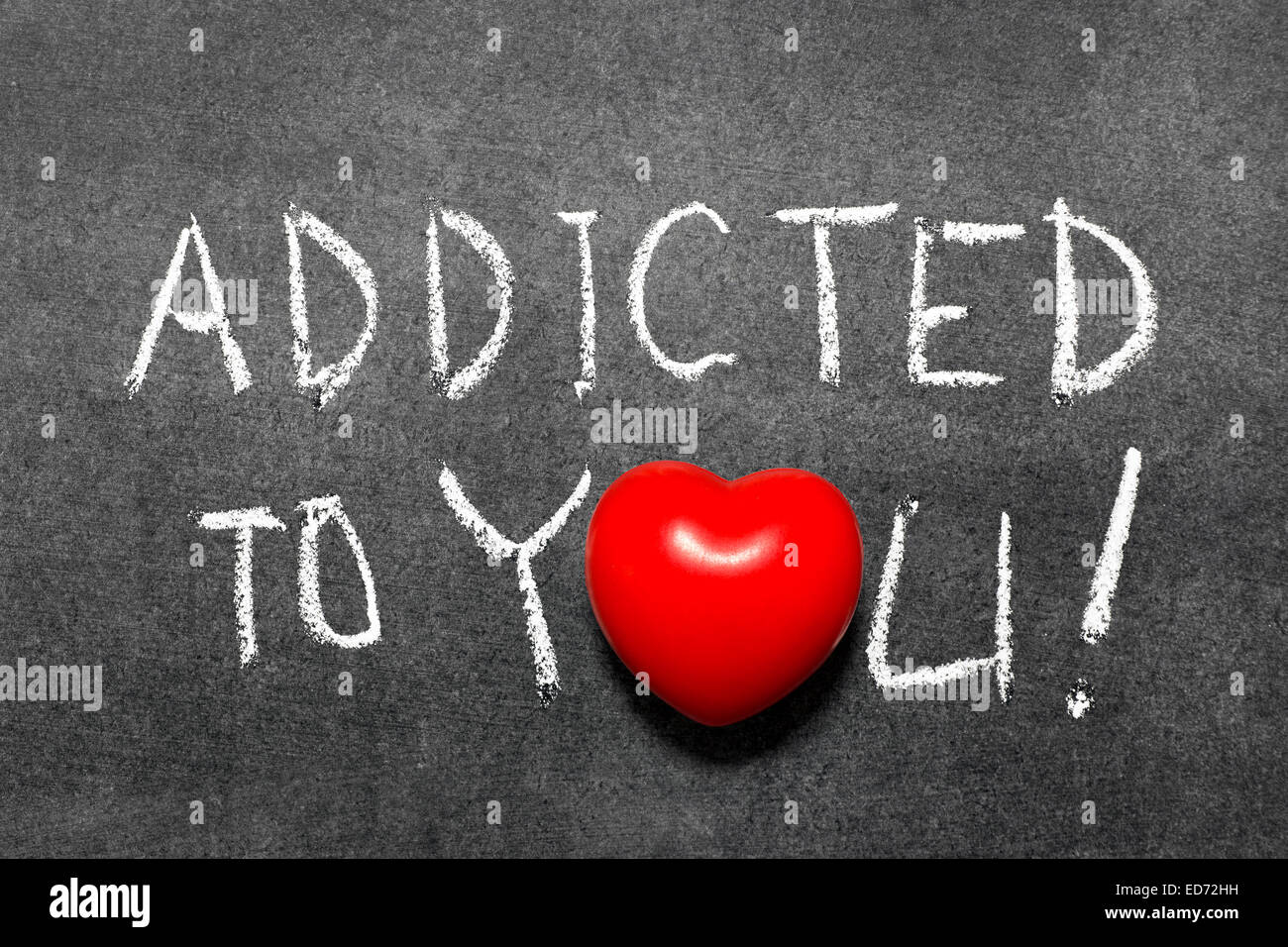 addicted to you phrase handwritten on blackboard with heart symbol instead of O Stock Photo