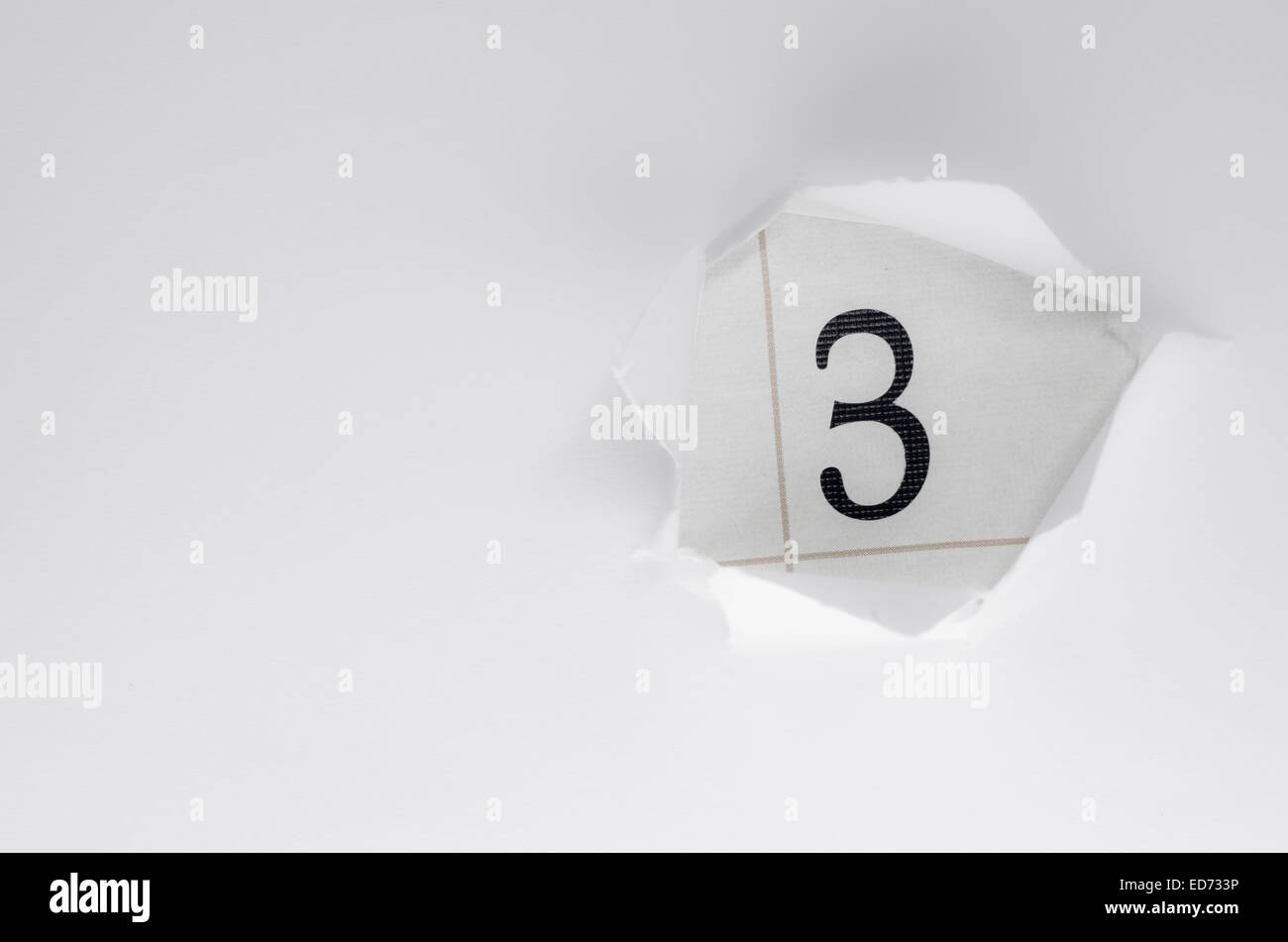 numbers seen through white ripped paper Stock Photo