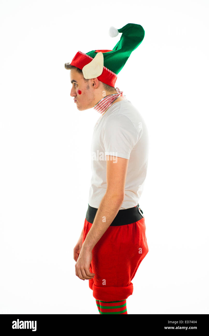 Santa's little helper: A young man in profile  at  a Christmas Xmas theme fancy dress 'office party' christmas party wearing an elf costume and looking unhappy, not enjoying himself, UK Stock Photo