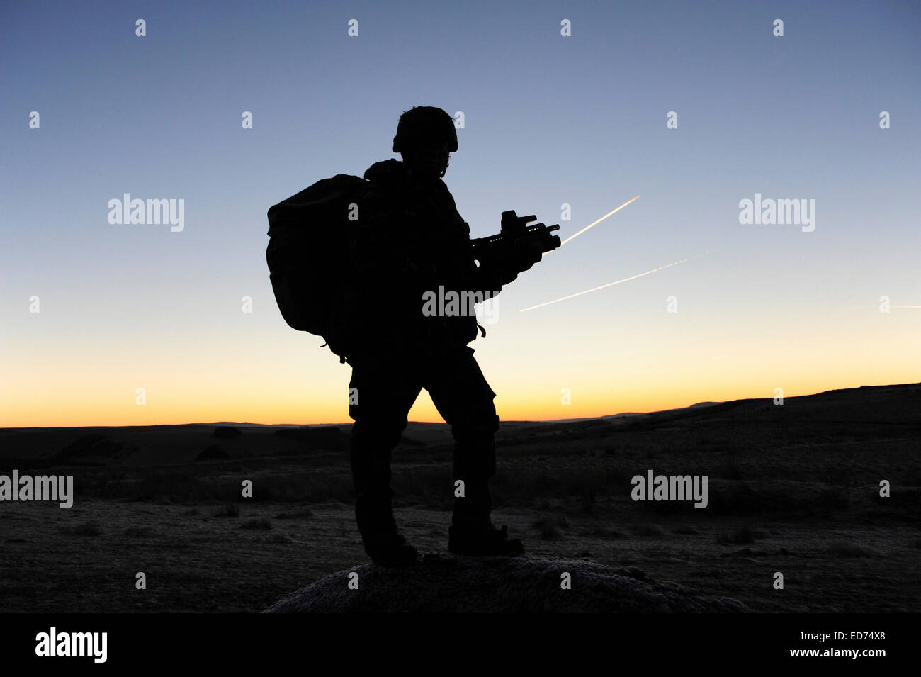 A British soldier on patrol as the Sun rises at Sennybridge Training Area, Wales, United Kingdom. Stock Photo