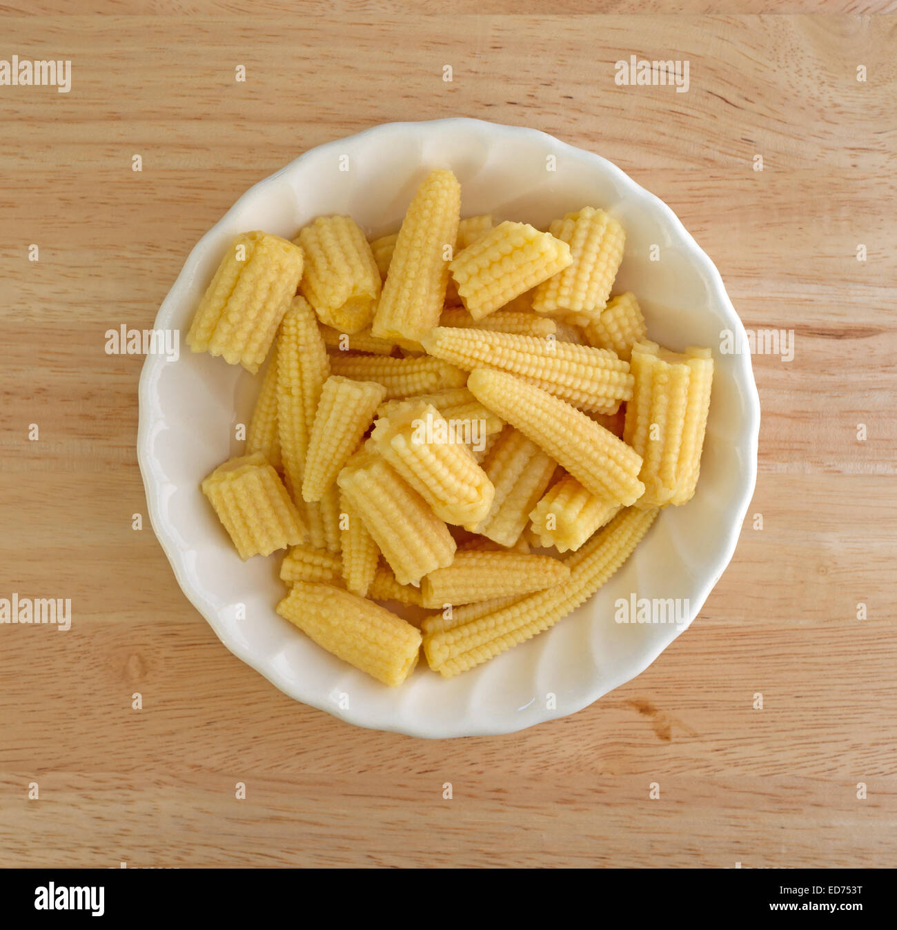 Top view of a bowl of corn nuggets in a small bowl atop a wood table. Stock Photo