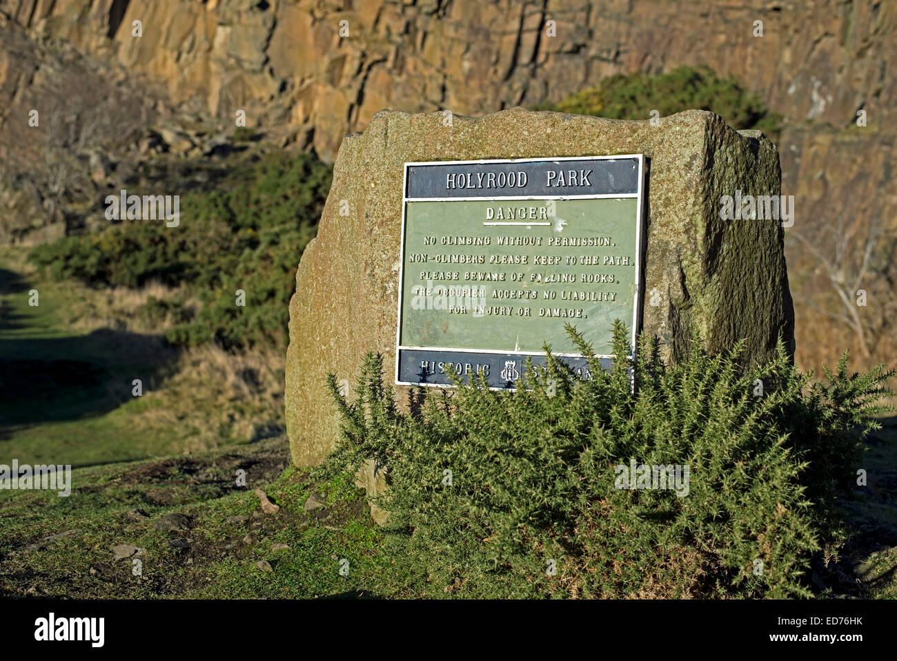 A sign in Holyrood Park Edinburgh warning of the dangers of climbing on nearby Salisbury Crags. Stock Photo