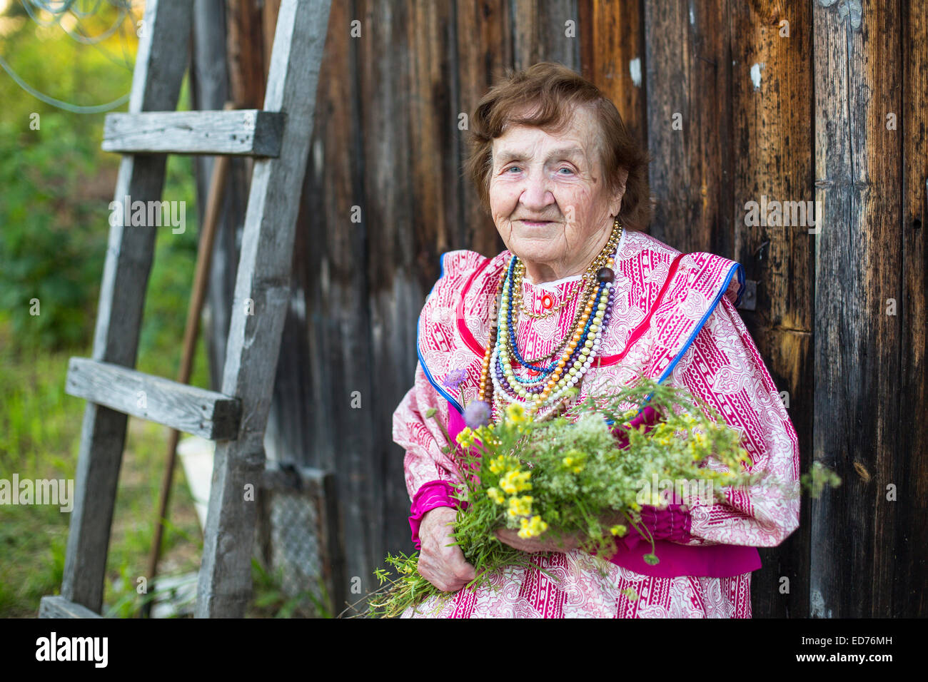 Old positive woman in the village, in a festive ethnic dress. Stock Photo