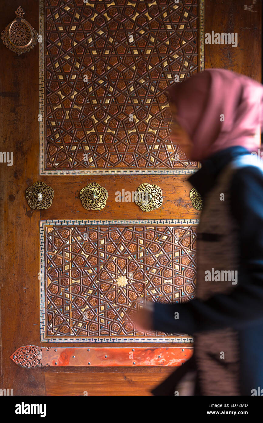 Muslim woman enters mosque by ornate carved entrance door, Suleymaniye Mosque, Istanbul, Republic of Turkey Stock Photo